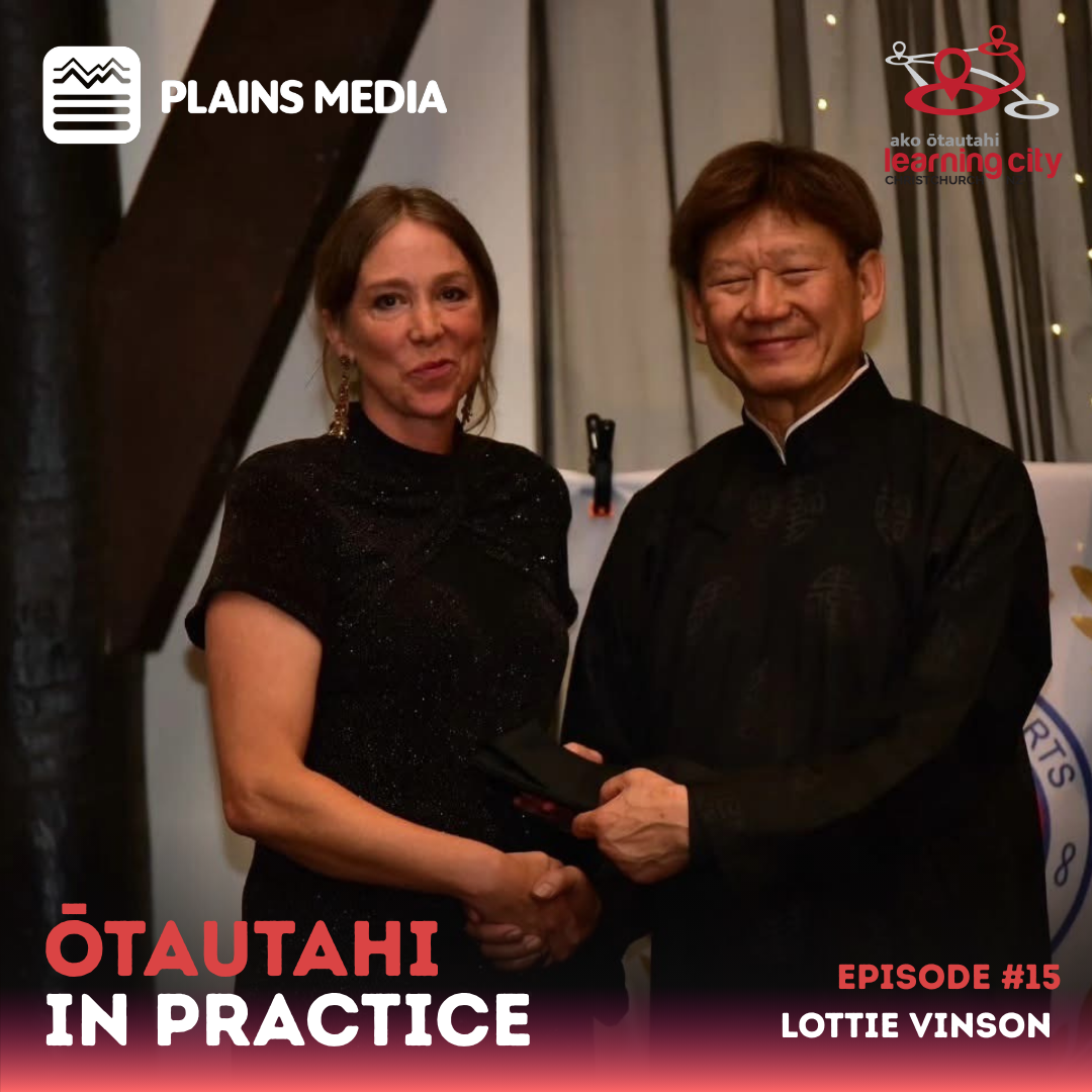 Lottie stands next to a happy looking ma. They both shake hands a they look at the camera