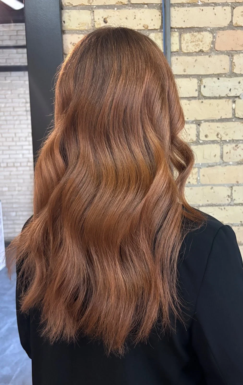 Studio M Aesthetics client with long, wavy copper hair.