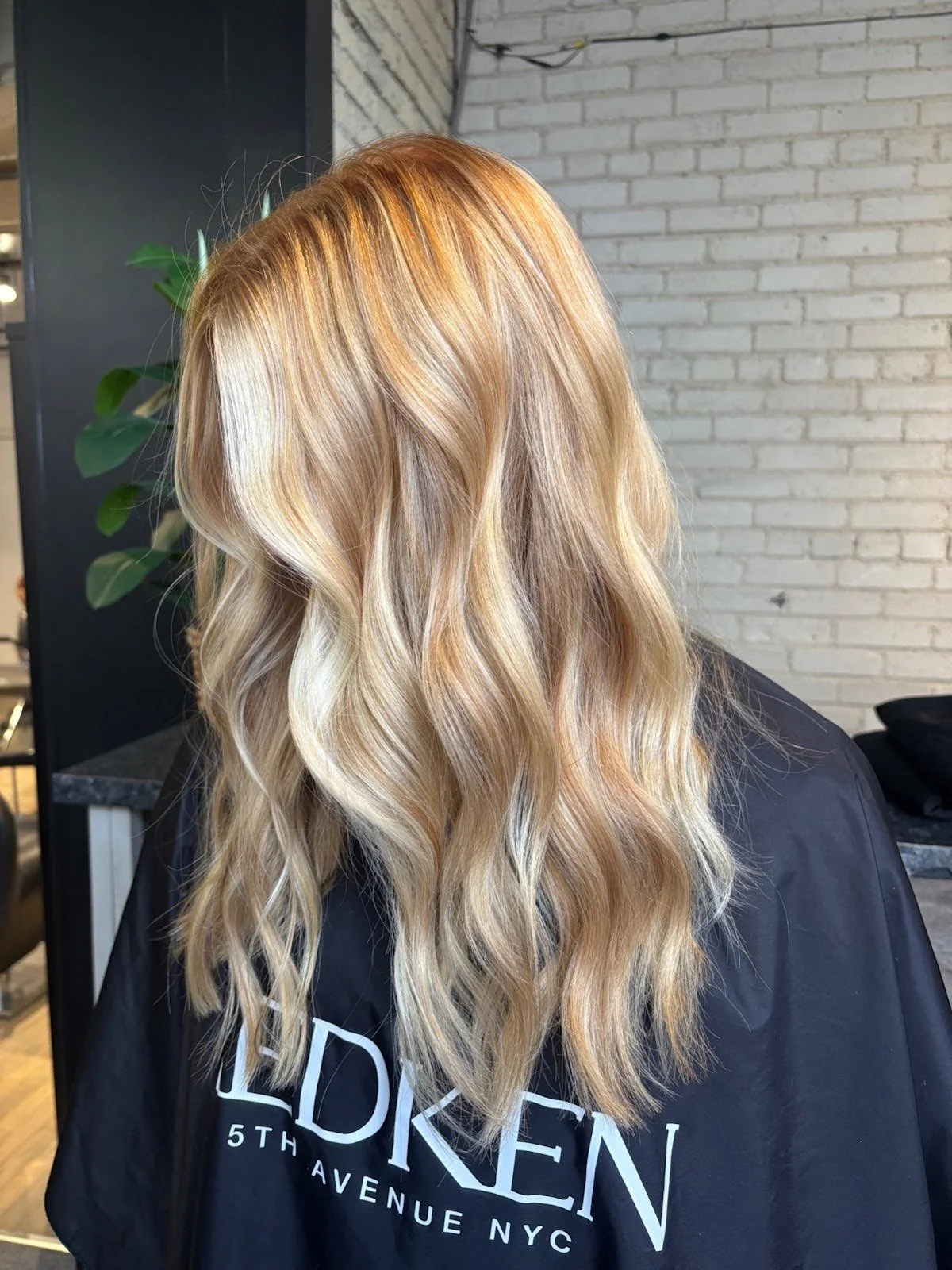 A Studio M Aesthetics client with long, wavy hair and a soft, lived-in blonde colour.