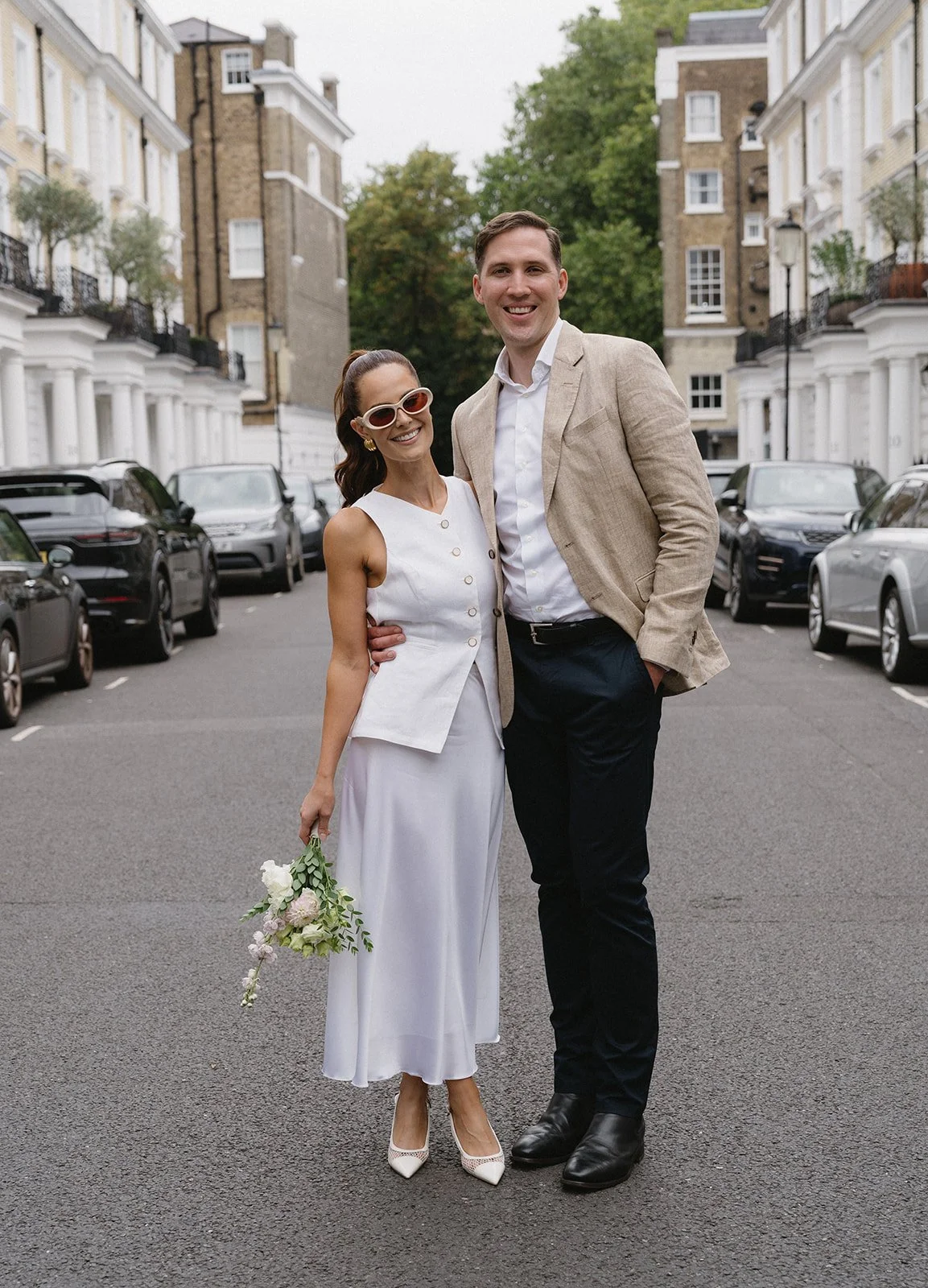 newlywed couple stand in the middle of a london street in chelsea after eloping at chelsea old town hall 