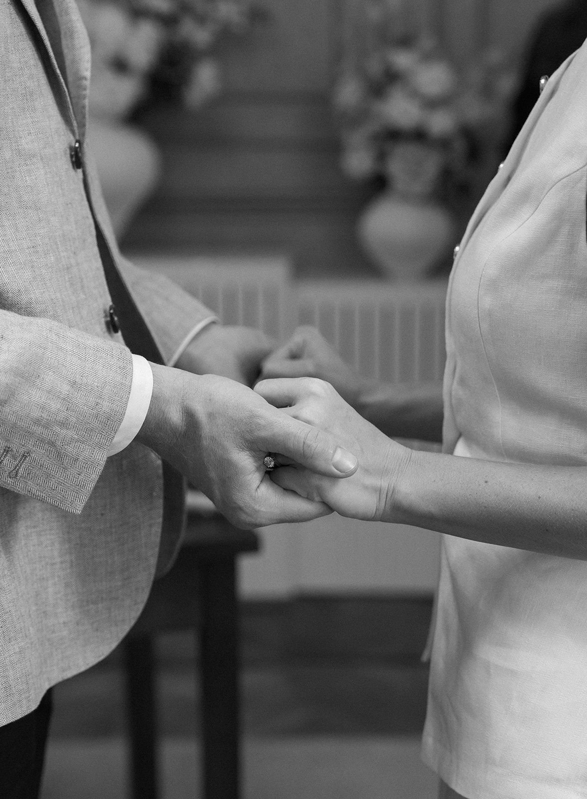A man and a woman holding hands during a wedding ceremony, with the man wearing a suit and the woman wearing a wedding dress.