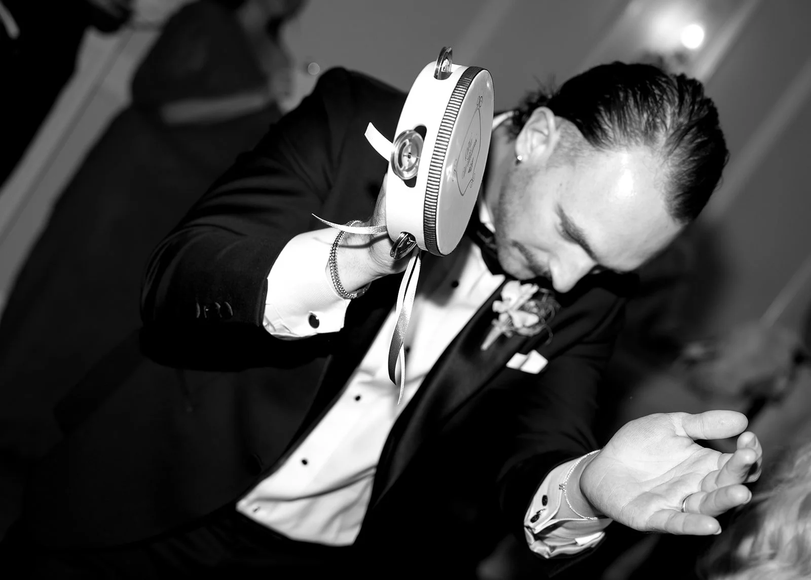 A woman in formal attire, holding a device near her shoulder, with her head bowed, preparing for a dance or performance.