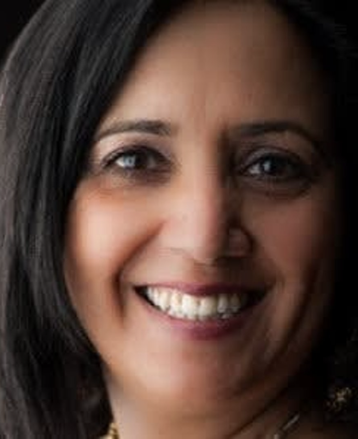 Close-up of a smiling woman with dark hair and tan skin.