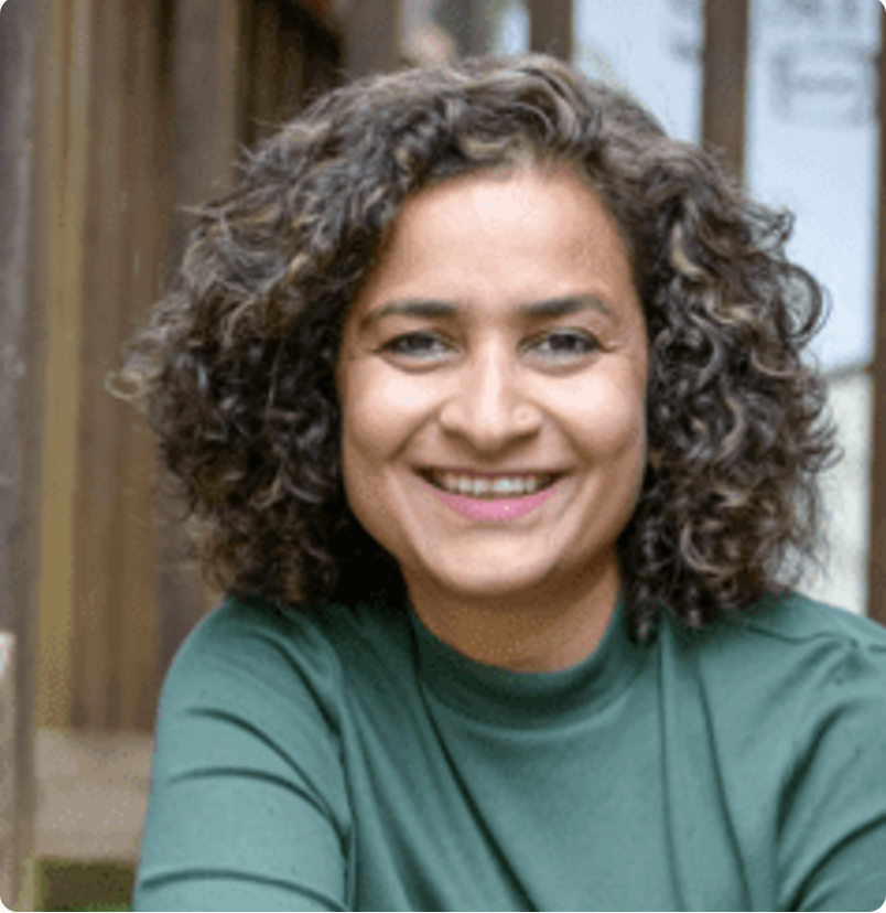 A woman with curly dark hair wearing a green shirt, smiling at the camera.