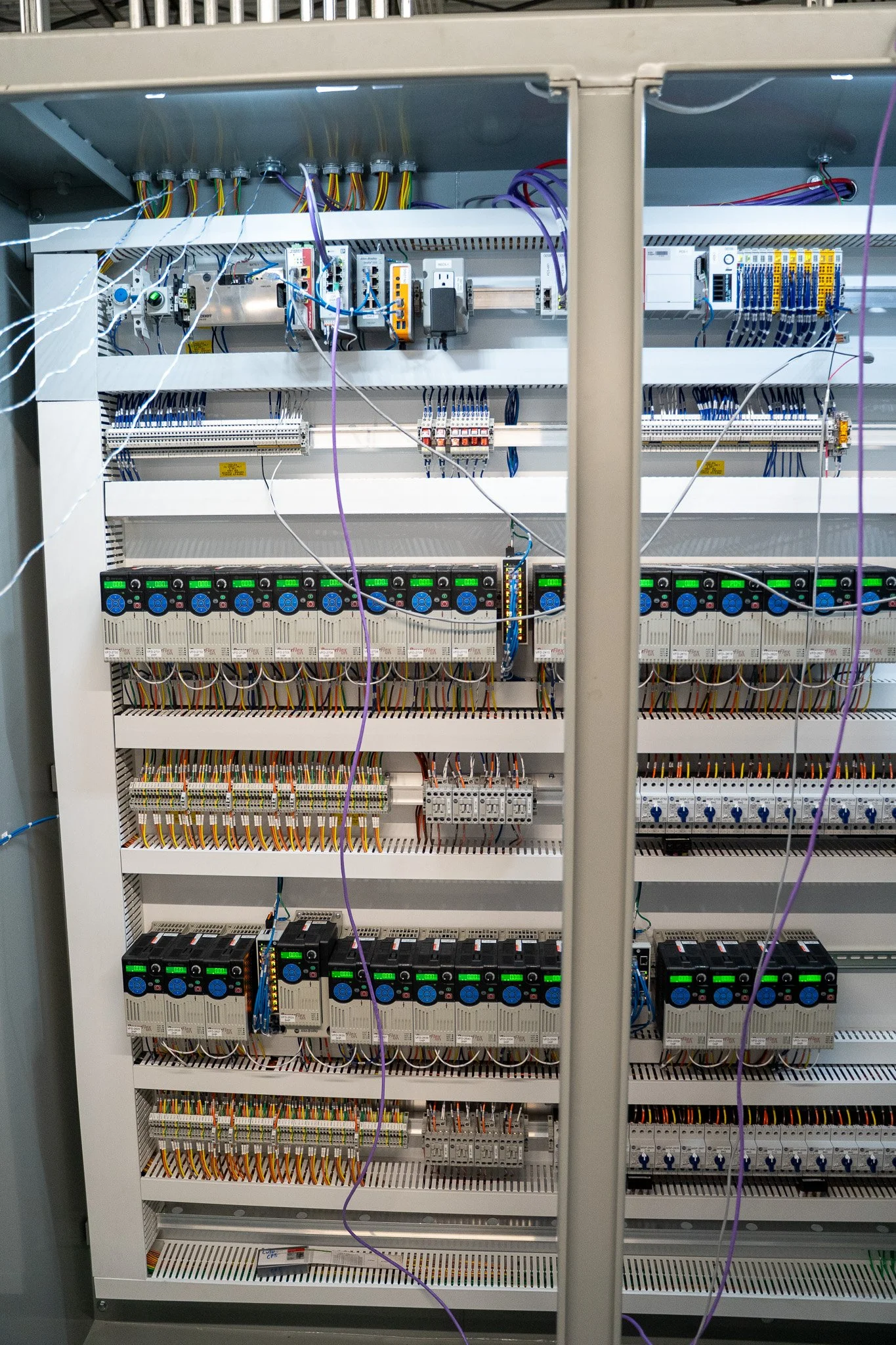 Close-up of an electrical control panel with various wires, circuit breakers, and electrical components.