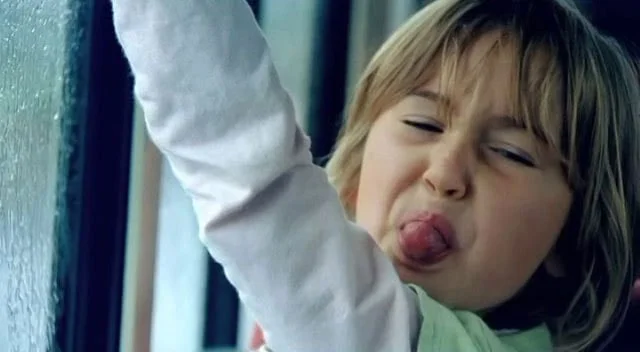 Child sticking out tongue and making a silly face.
