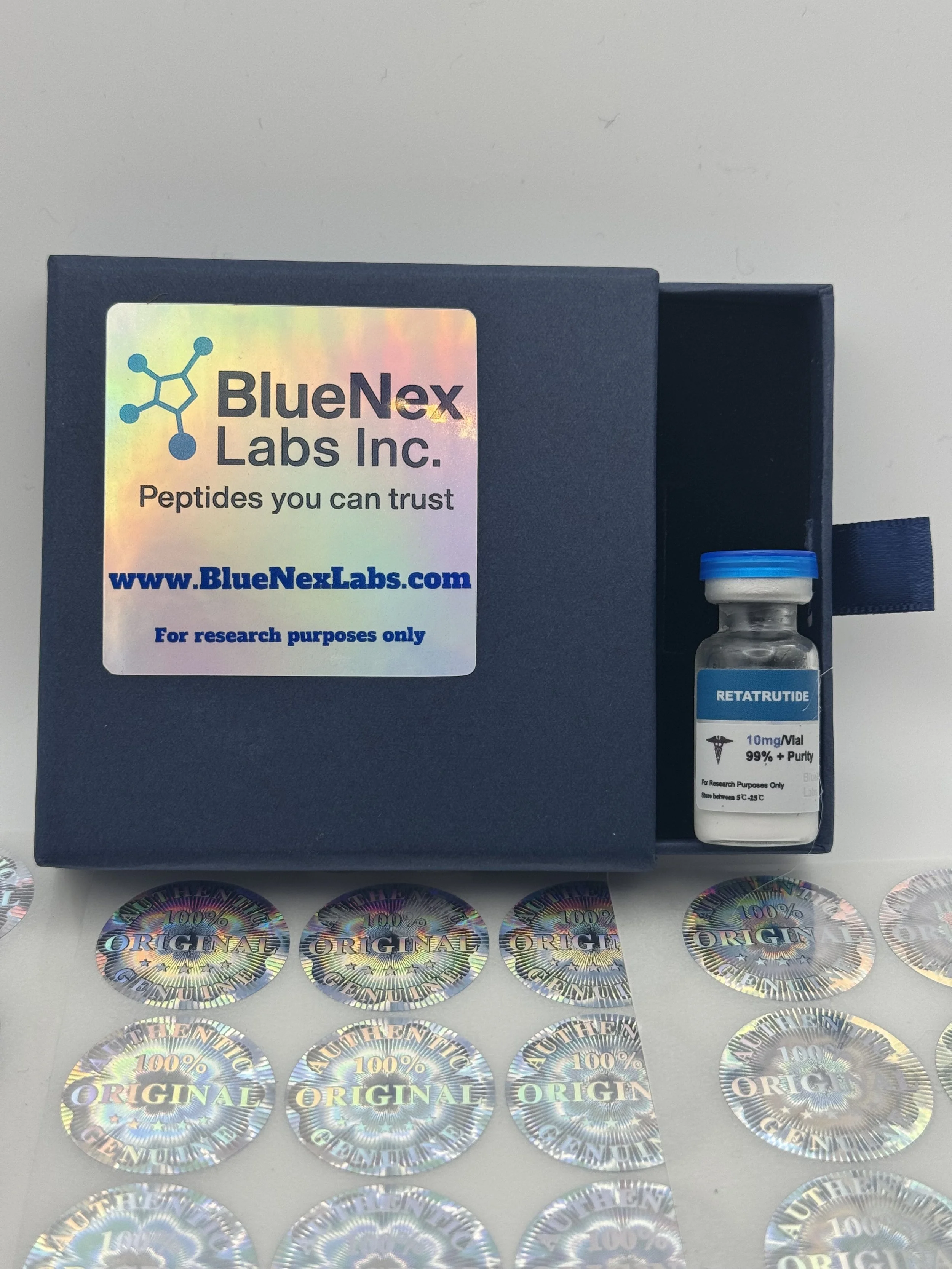 A blue box from BlueNex Labs Inc. containing a small glass vial labeled 'RETATRUTIDE' with a blue cap, surrounded by holographic stickers that say '100% ORIGINAL' and 'AUTHENTIC'.