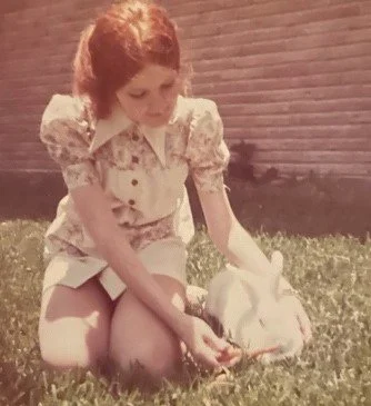 Women sitting in grass petting a small rabbit