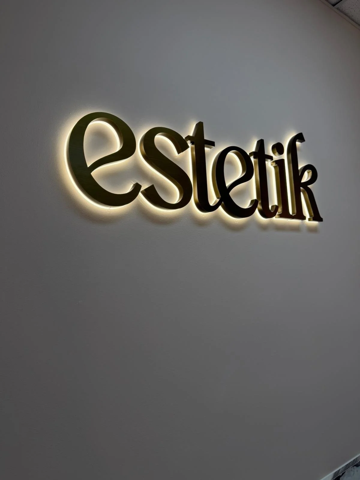 Estetik gold backlit LED sign on dark wall - halo-lit illuminated signage Adelaide SA