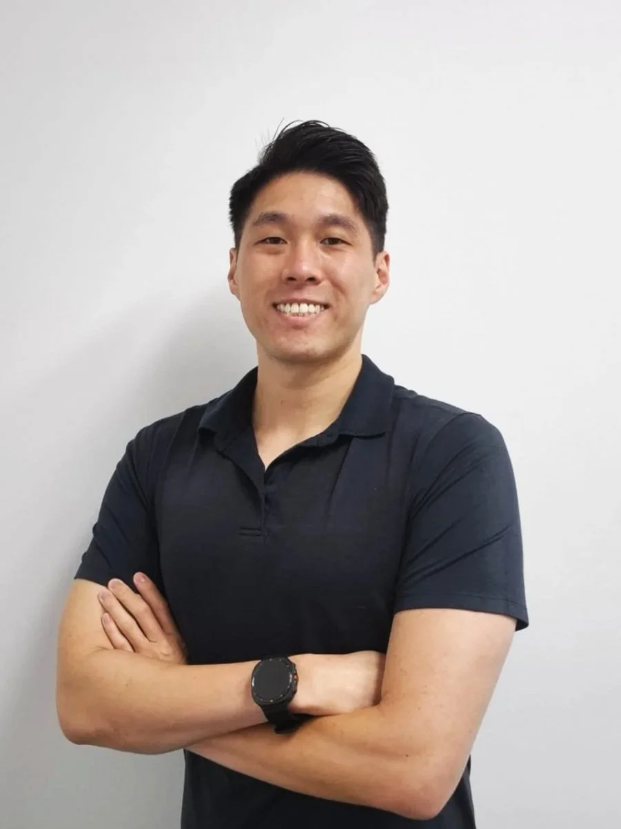 A smiling woman with glasses, hoop earrings, short curly hair, wearing layered necklaces and a striped blouse.