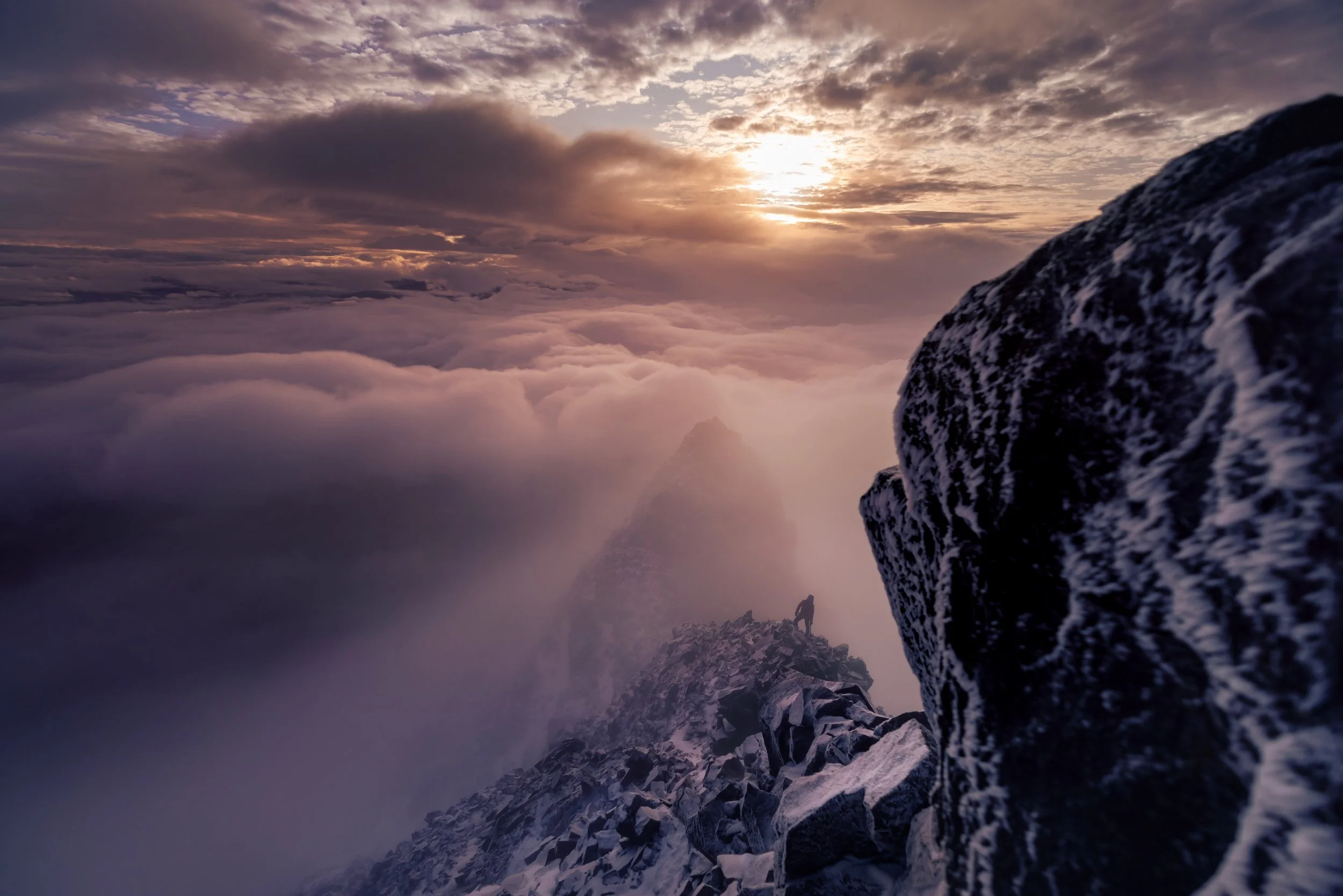A person climbing a snowy mountain ridge in Equador during sunrise or sunset, surrounded by clouds and mist.