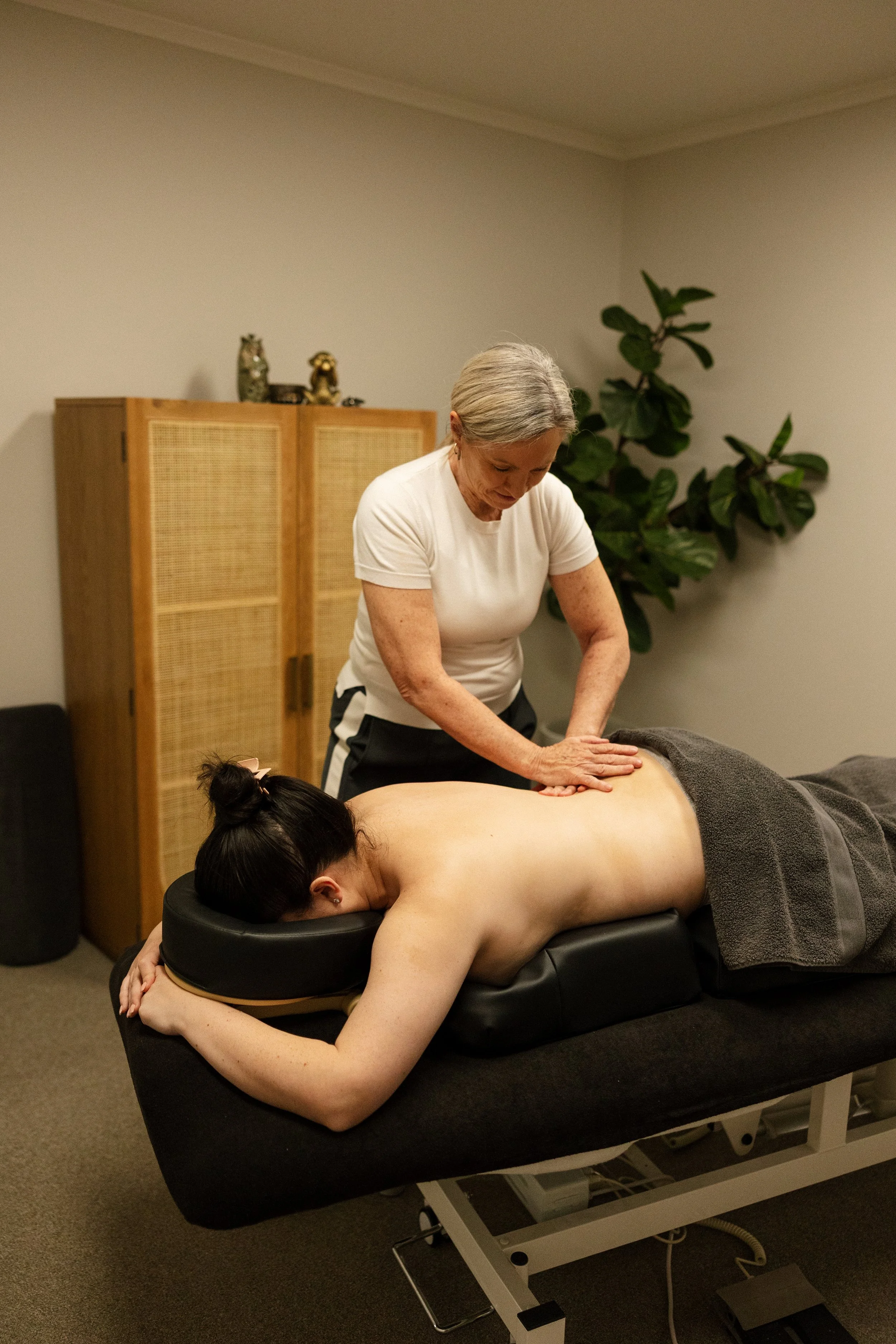 A woman receiving a back massage from a massage therapist in a spa or massage clinic.