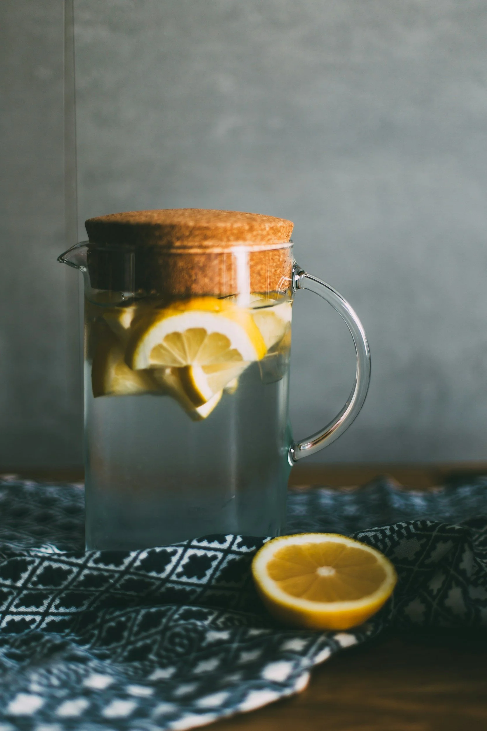 Glass jar filled with water and lemon slices on a countertop.