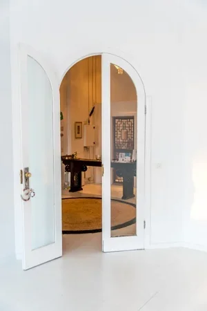 View of a white interior door with mirrored panels, partially open, revealing a foyer with a staircase and a hallway with decor.