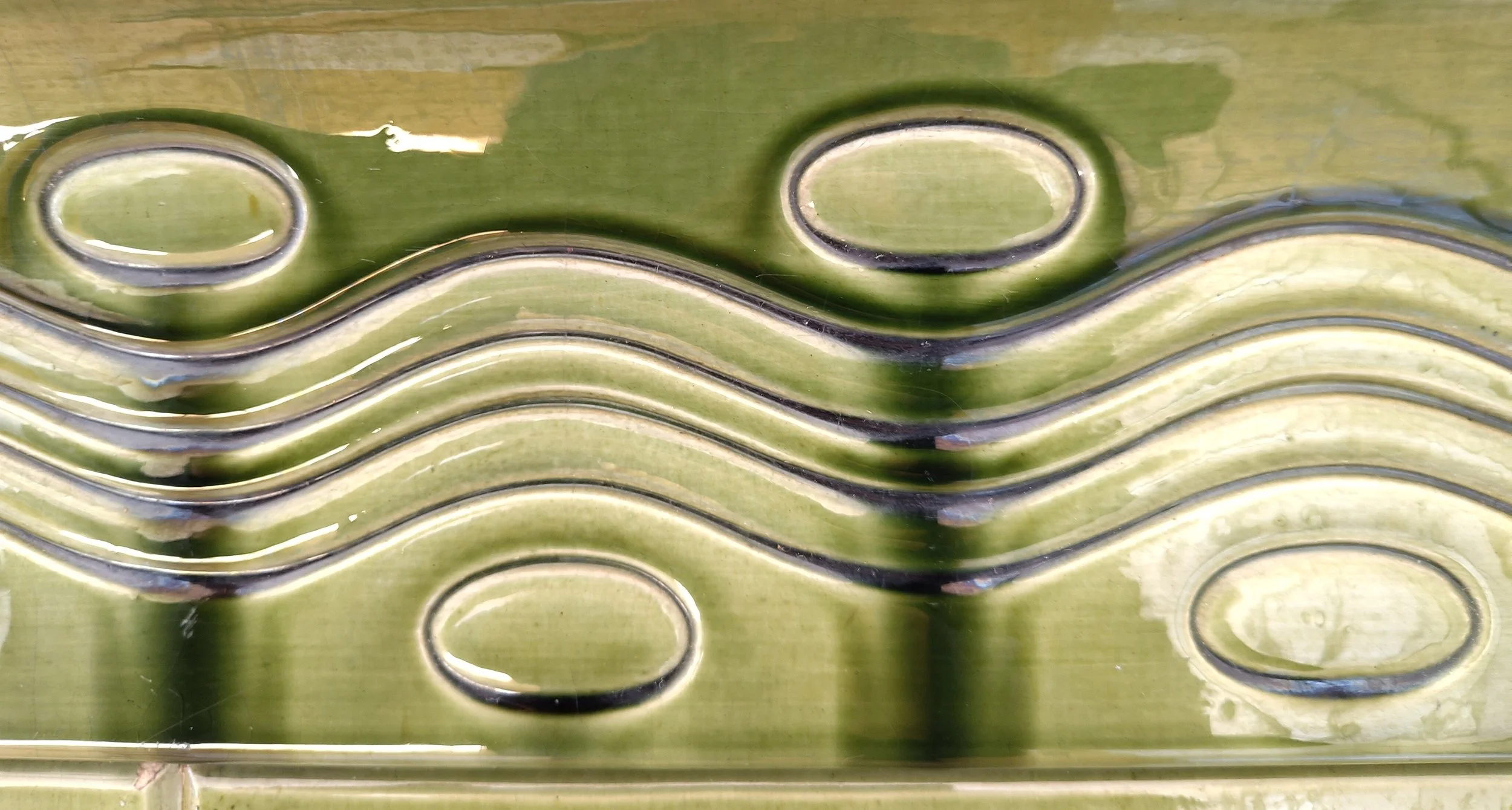 Nahaufnahme eines gefalteten grünen Blattstiels mit ovalen Mustern und Wellen, vermutlich bei der Pflanzenverarbeitung.