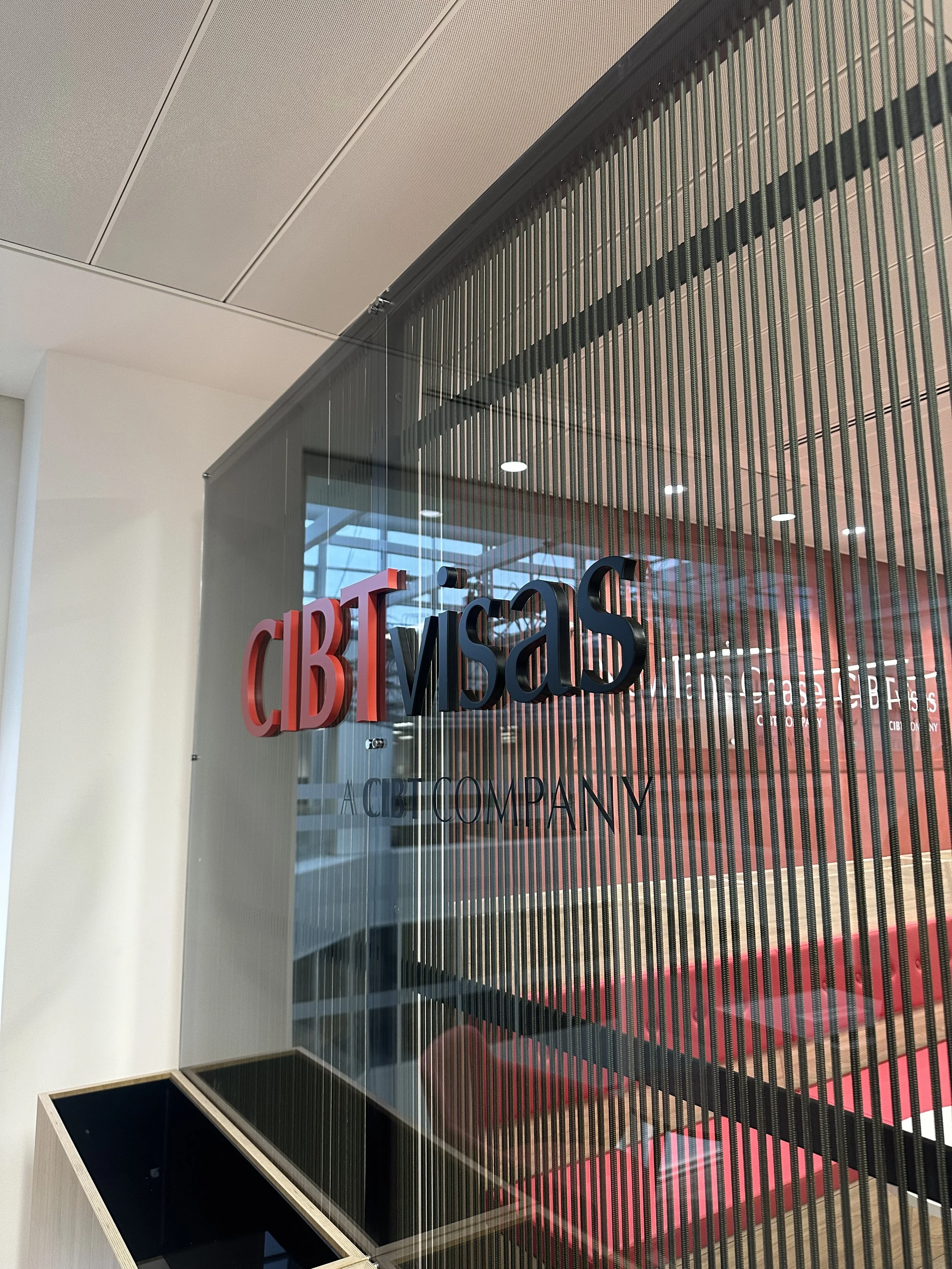 A acrylic panel with the words 'CIB VISA' in red and black text, set against a metal slatted background in an office or bank lobby.
