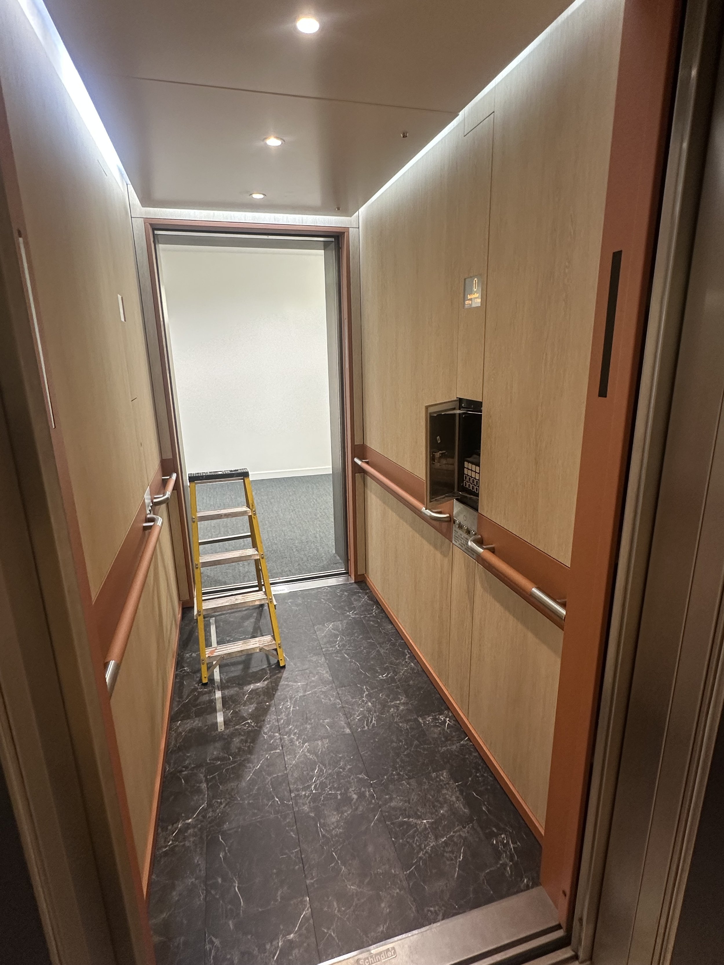 a lift refurbished with the walls and panels wrapped in architectural wood.