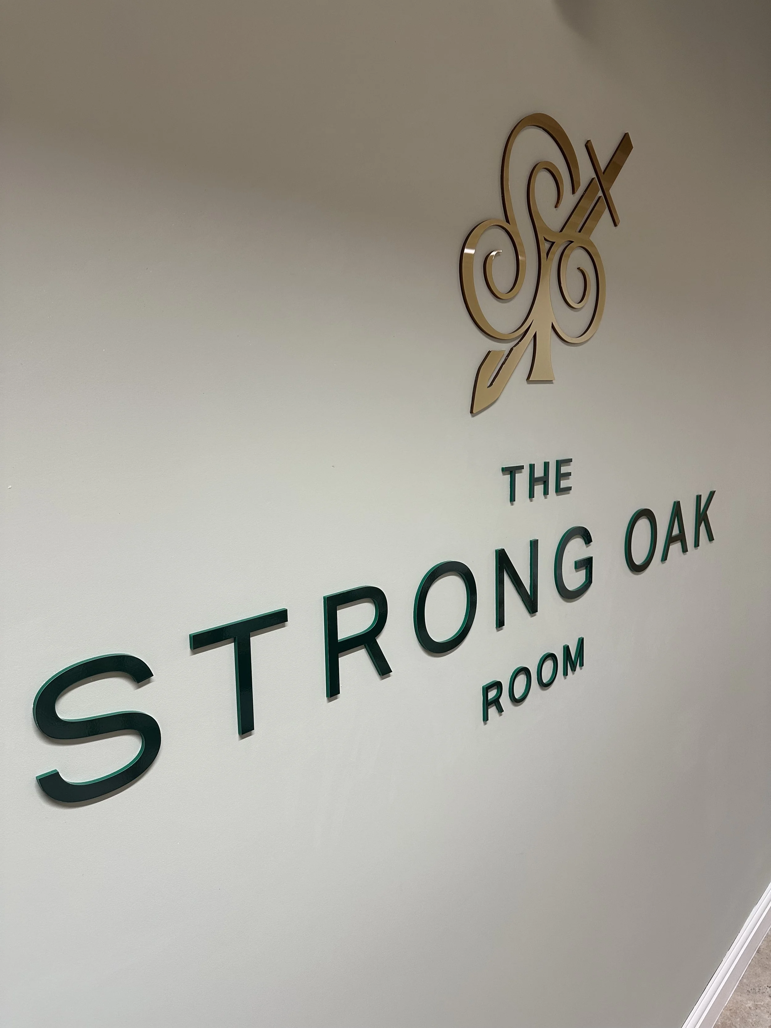 acrylic lettering Close-up of wall sign with stylized logo and partially visible text reading 'THE STRONG OAK.'
