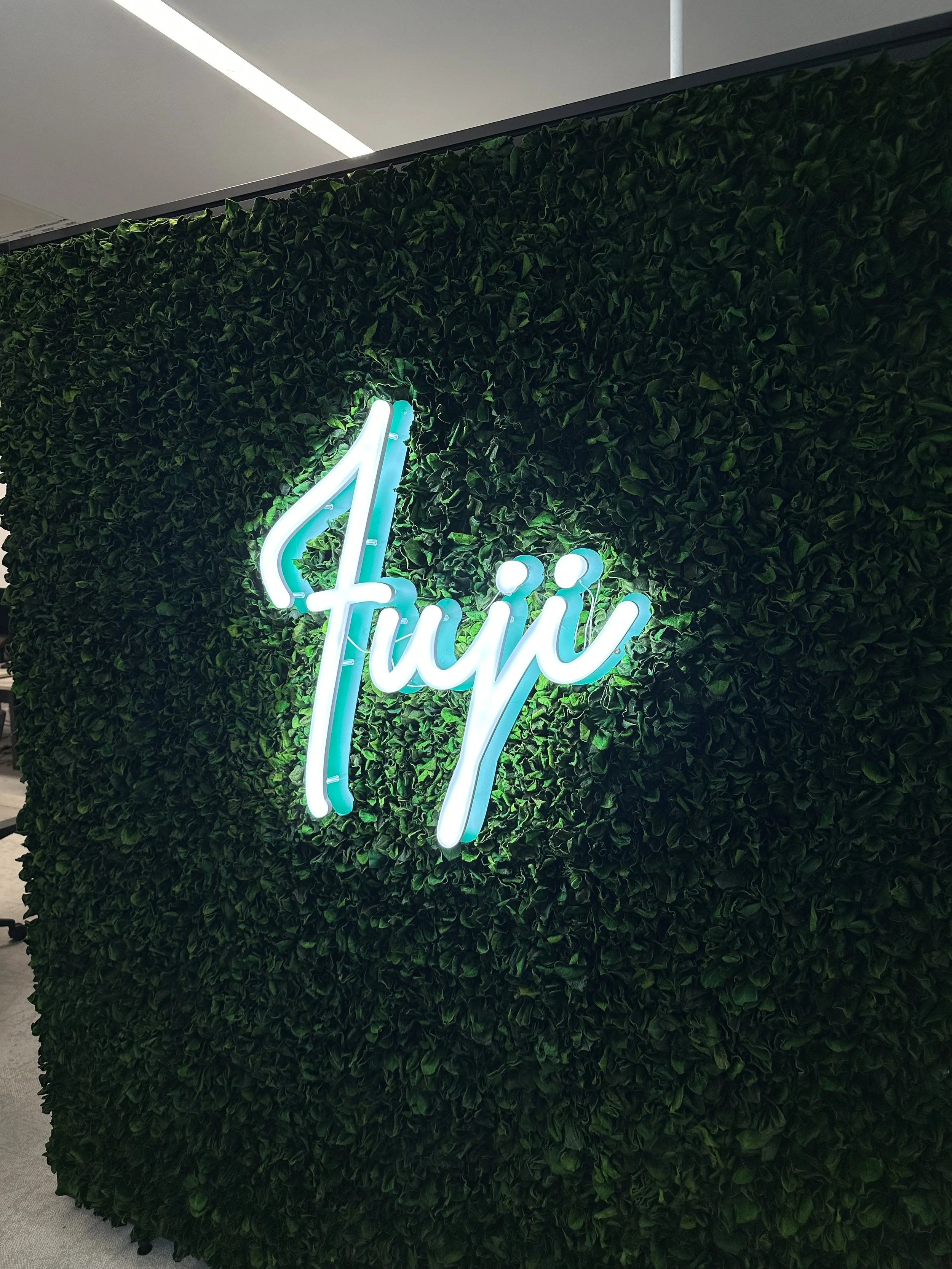 led illuminated sign saying "fuji" on flower wall background.