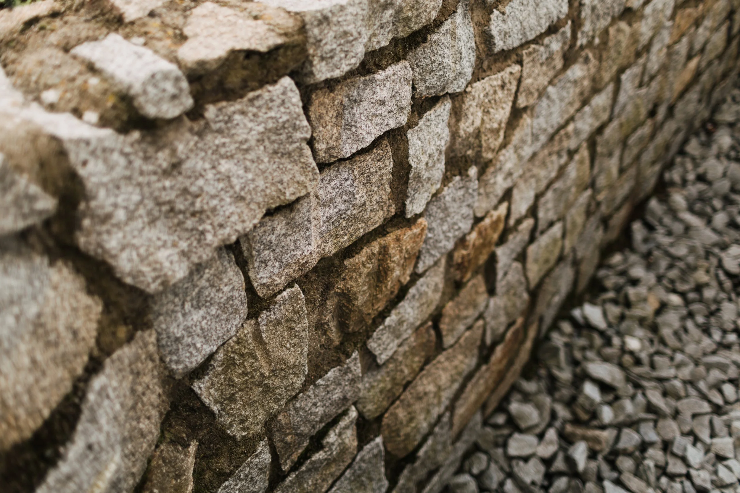 Nahaufnahme einer Steinmauer mit unregelmäßigen, grauen Steinen