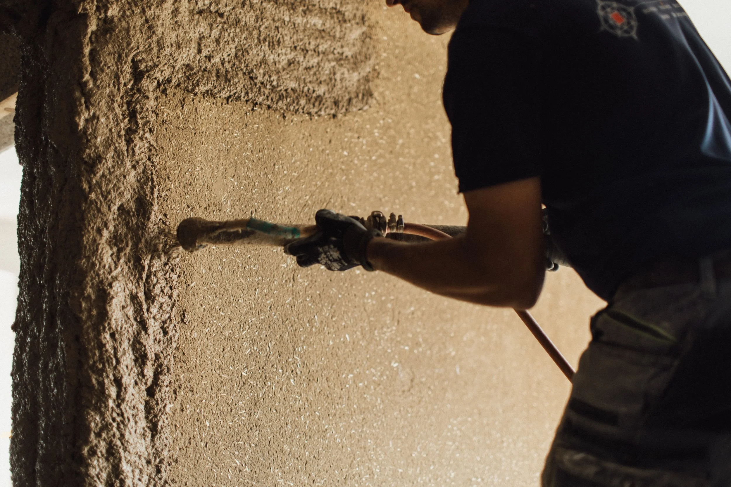 Ein Arbeiter schaufelt Erde oder Sand mit einem kleinen Schieber auf einer Baustelle.