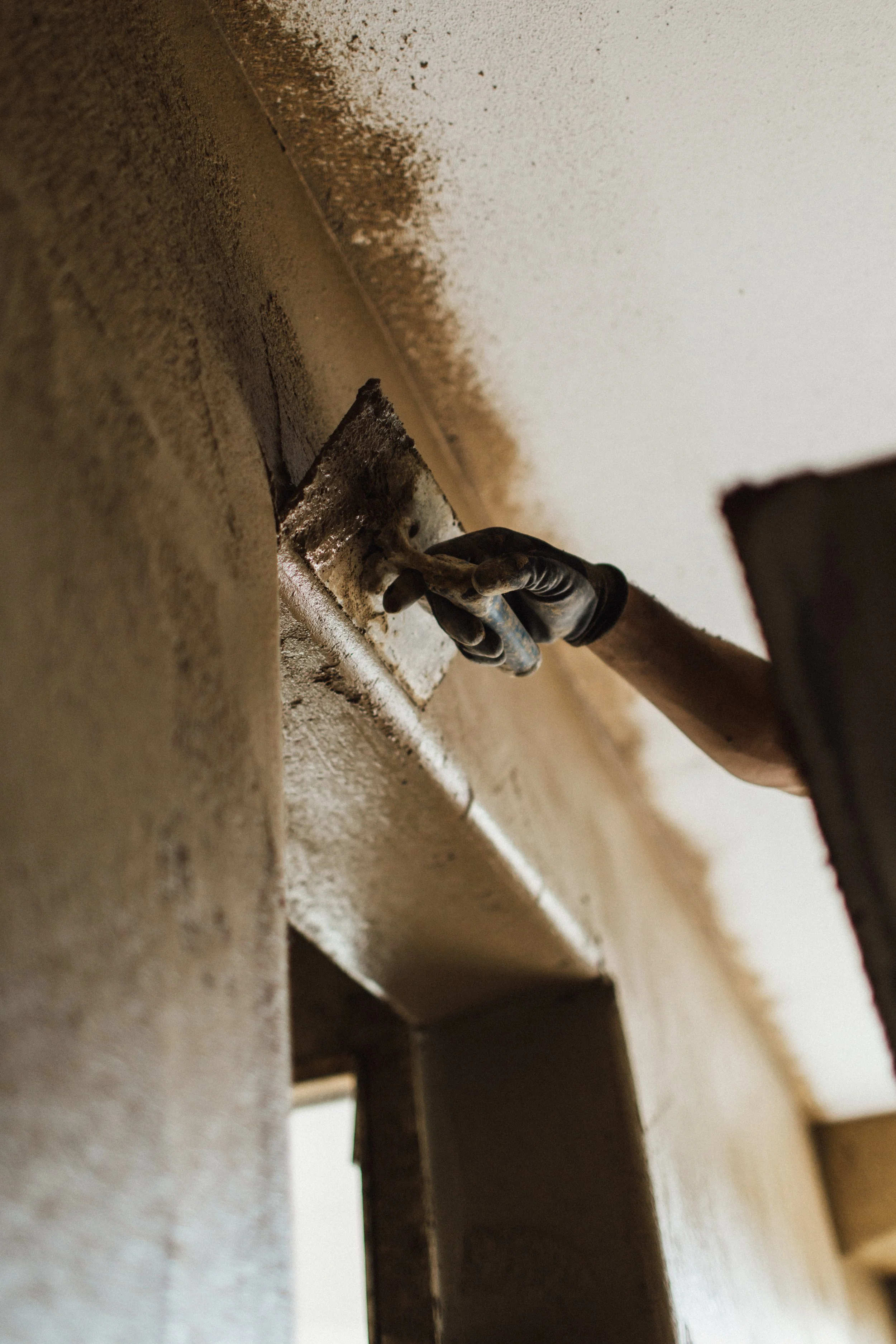 Handwerker bei der Arbeit, der eine Wandverkleidung anbringt oder repariert, mit Werkzeug in Hand.