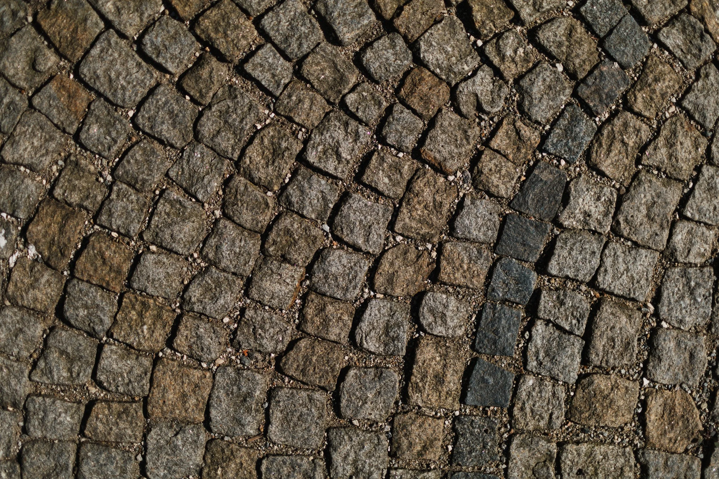 Nahaufnahme von Kopfsteinpflaster mit unterschiedlichen Farbtönen und Texturen.