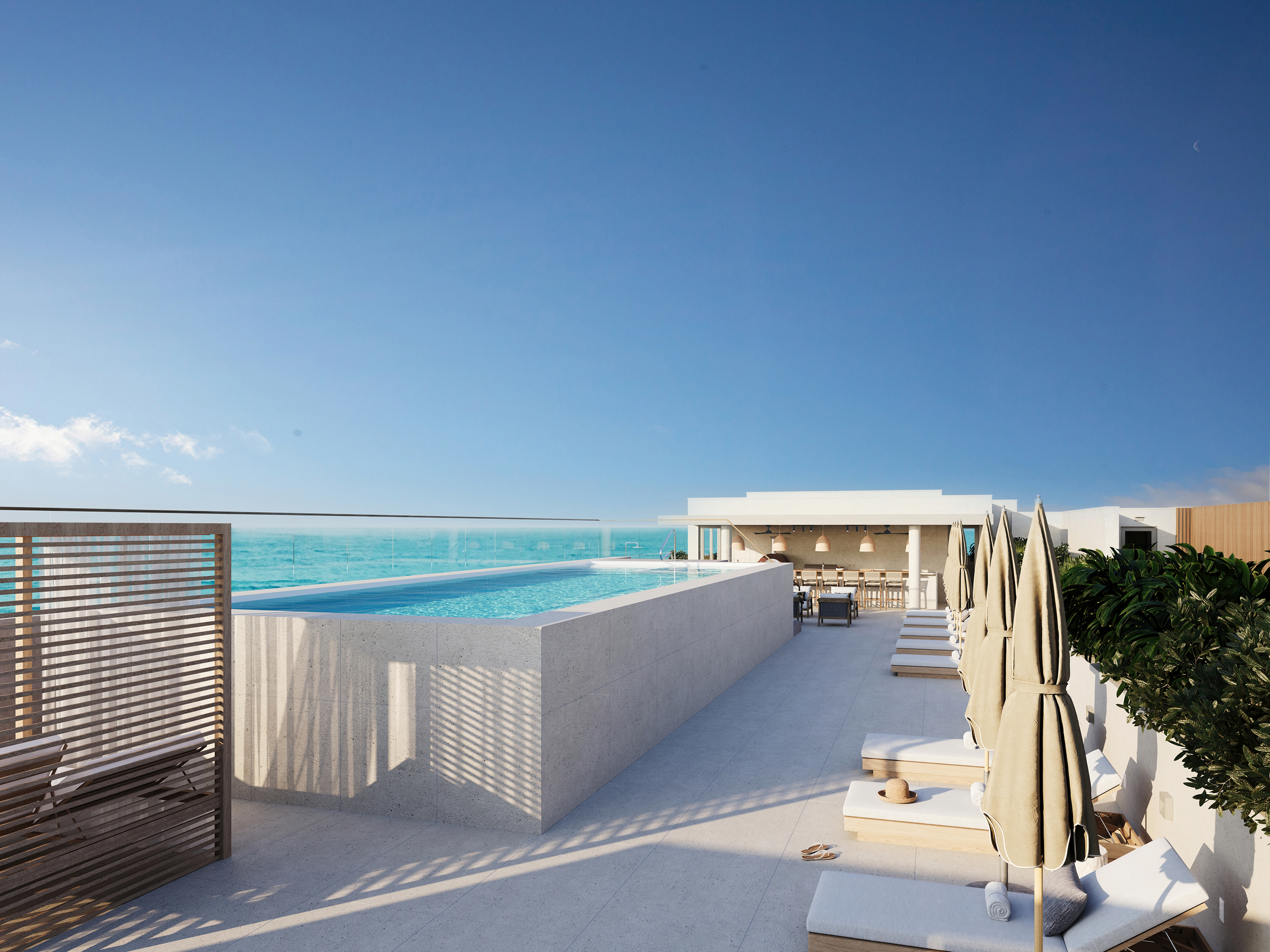 Rooftop with outdoor pool, lounge chairs with umbrellas, and ocean view at sunset.