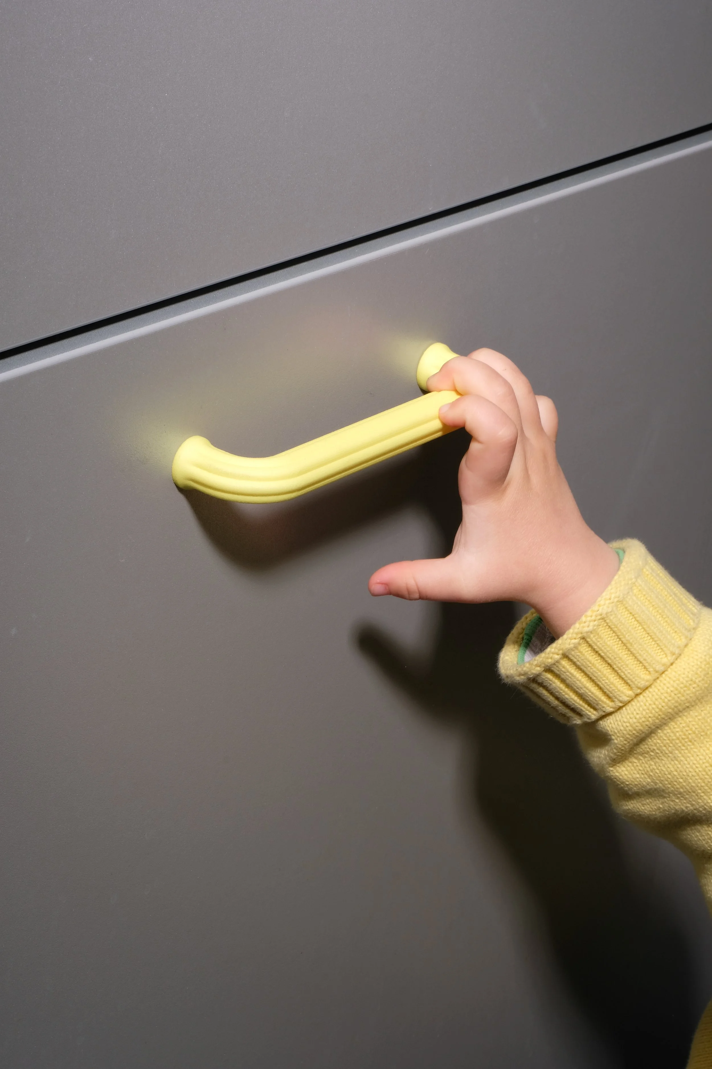 Hand hält einen gelben Eiskratzer vor einer vereisten Autoscheibe.