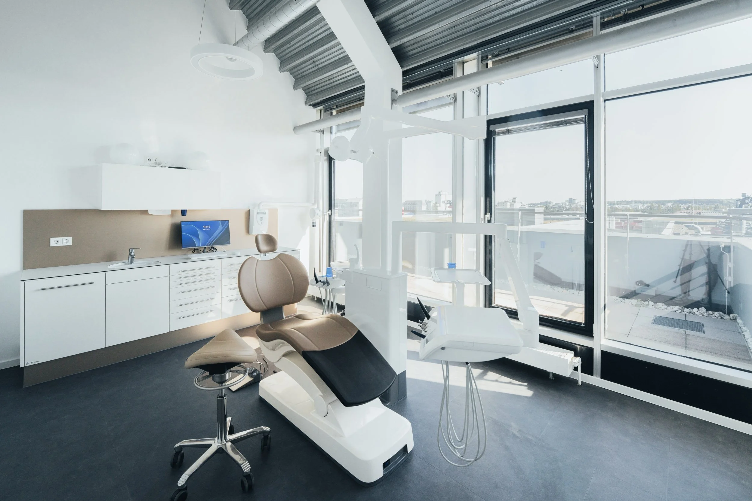 Modern dental clinic with dental chair, equipment, and large windows showing a cityscape.