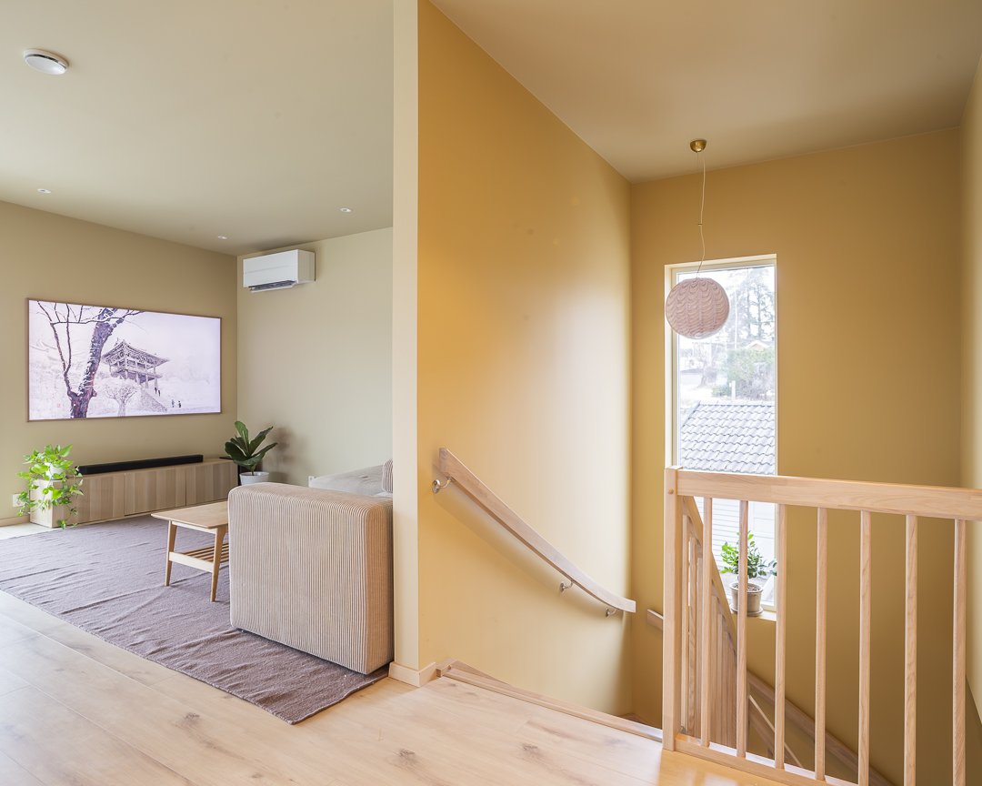 Et lys og moderne oppholdsrom med stor TV, sofa, illustrasjonsbilde av et hjem, med grønne planter, naturlig lys og minimalistisk innredning.