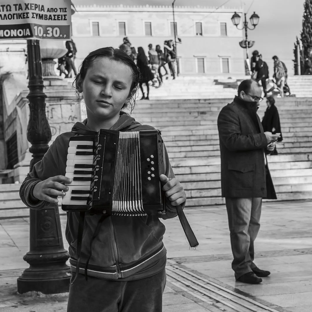 Jente spiller trekkspill foran Syntagmapalasset i Athen.