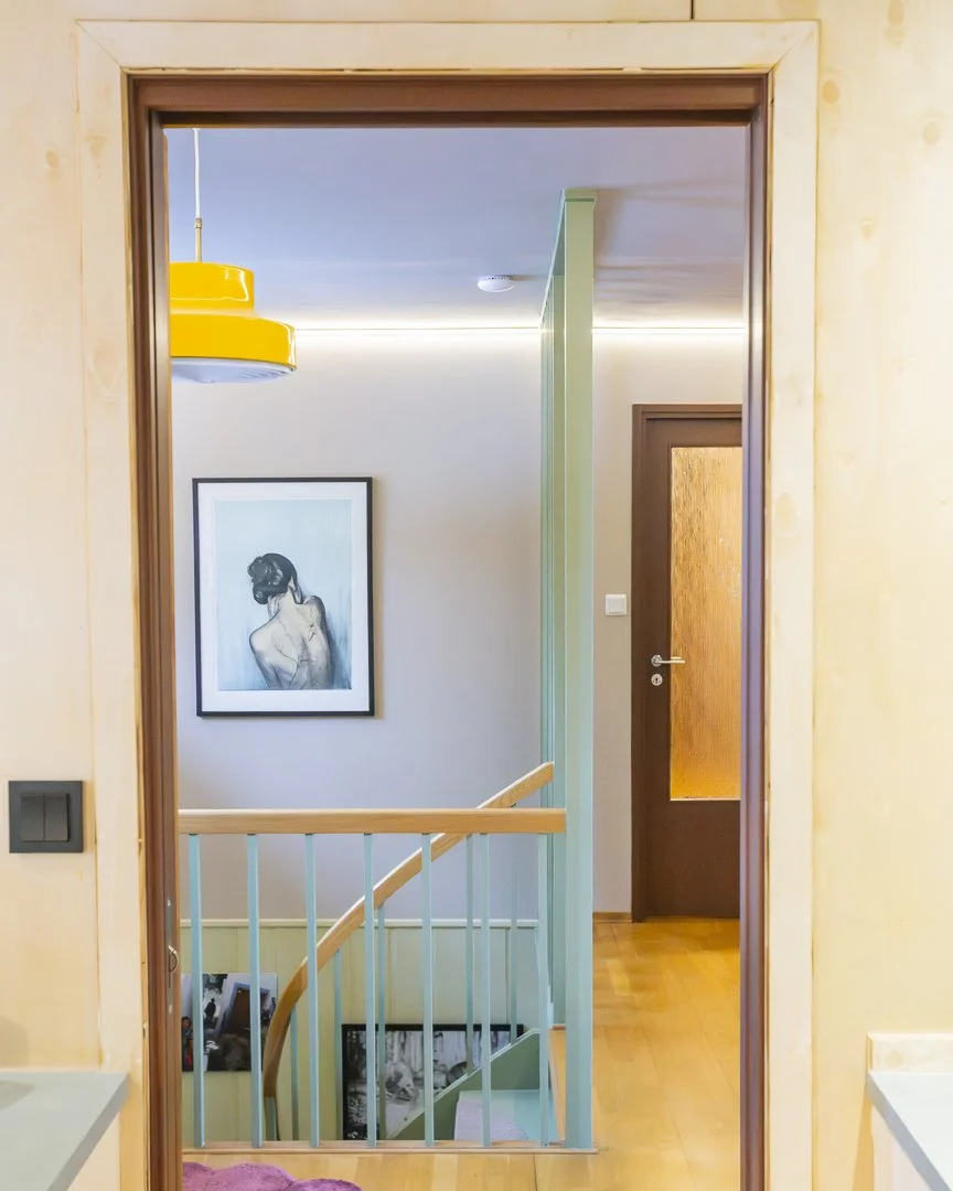 Innvendig utsikt fra et rom mot en trappeløp med en vegg, en malt personlig kunst av en kvinnes rygg, og en ytterdør med glassfylling.