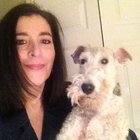 A woman taking a selfie with a white dog near a cabinet