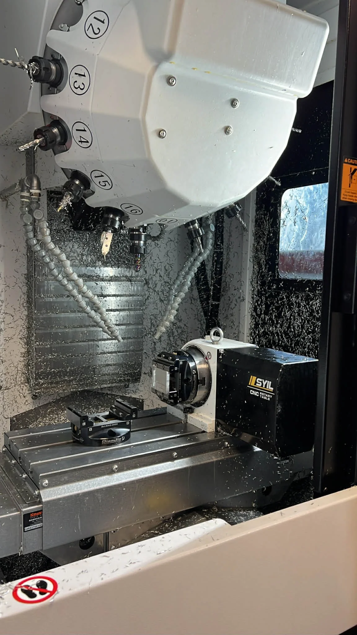 A CNC milling machine in operation with metal shavings scattered around, and a spindle holding a cutting tool.