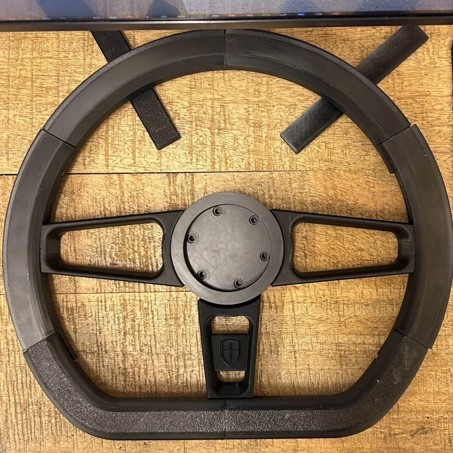 A black racing wheel for a gaming steering simulator placed on a wooden surface.