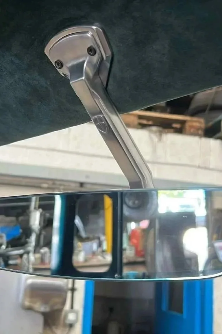 Close-up of a vehicle's interior, showing a rearview mirror attached to the ceiling.