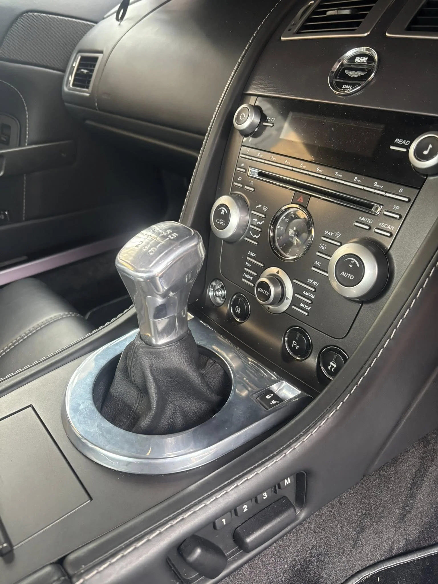 Interior of a car showing the gear shift, center console with buttons and controls, and part of the dashboard.