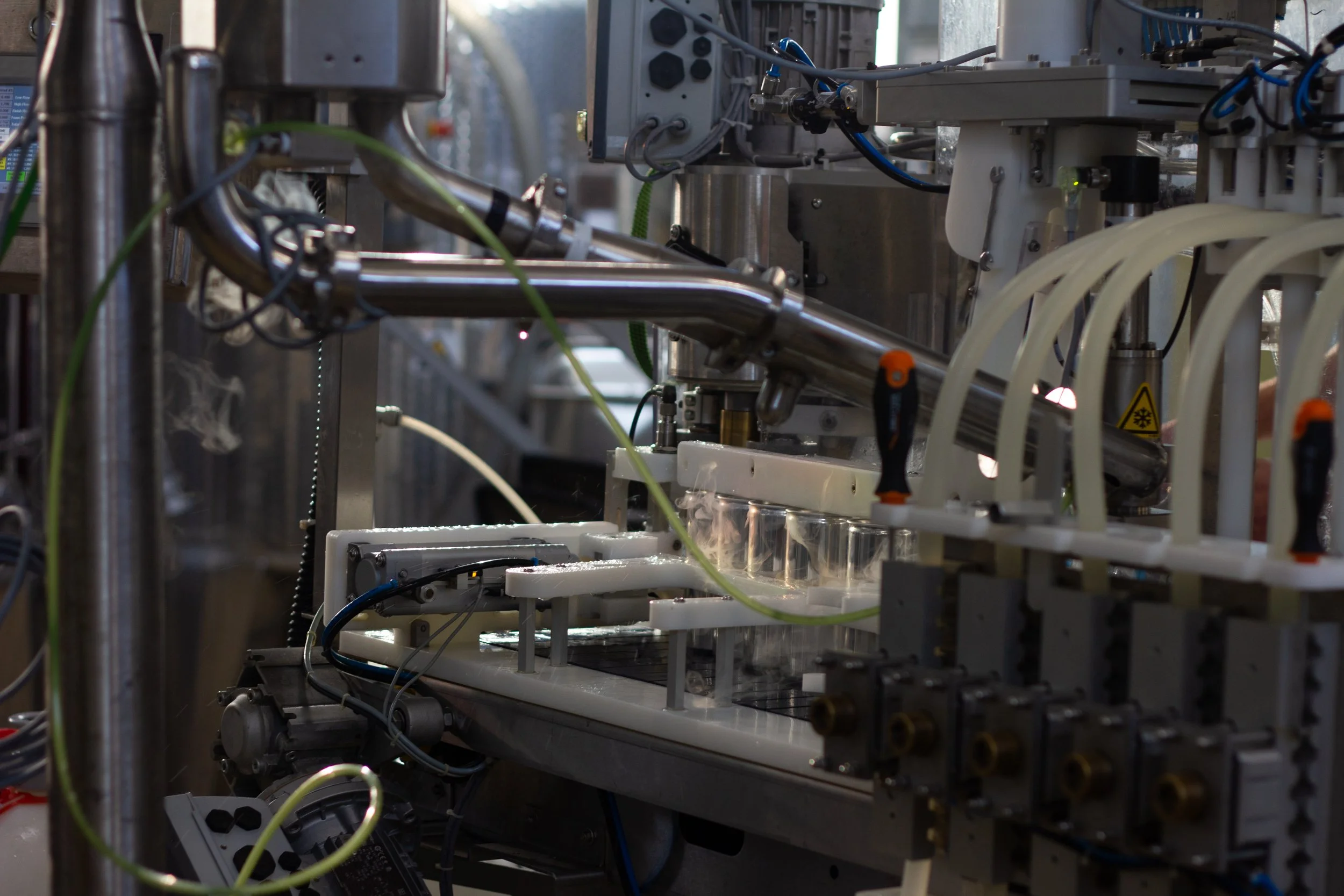 Close-up of scientific or industrial machinery with metal pipes, wires, and glass containers, used for experiments or manufacturing processes.