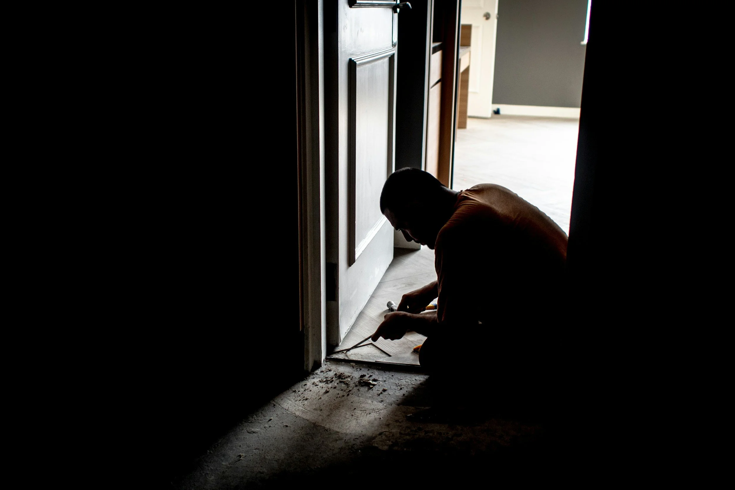 A construction worker removing old flooring near a doorway during a property refurbishment project by MSI Property Group.