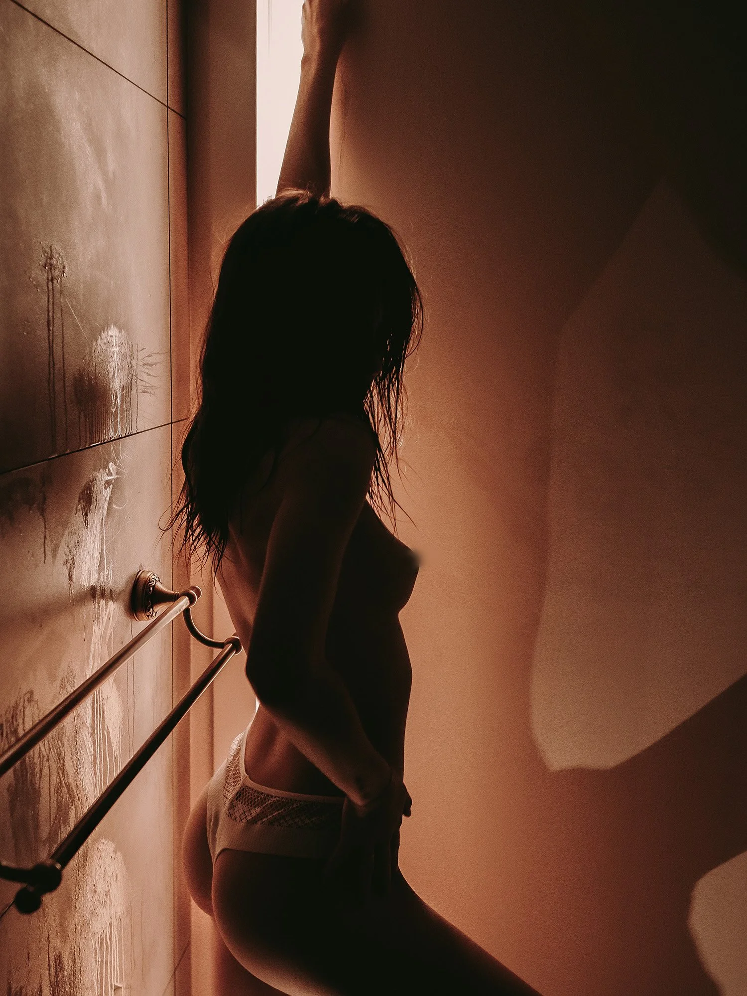 Silhouette d'une femme aux cheveux longs, portant un débardeur blanc, penchée en avant dans une pièce sombre avec lumière de derrière.