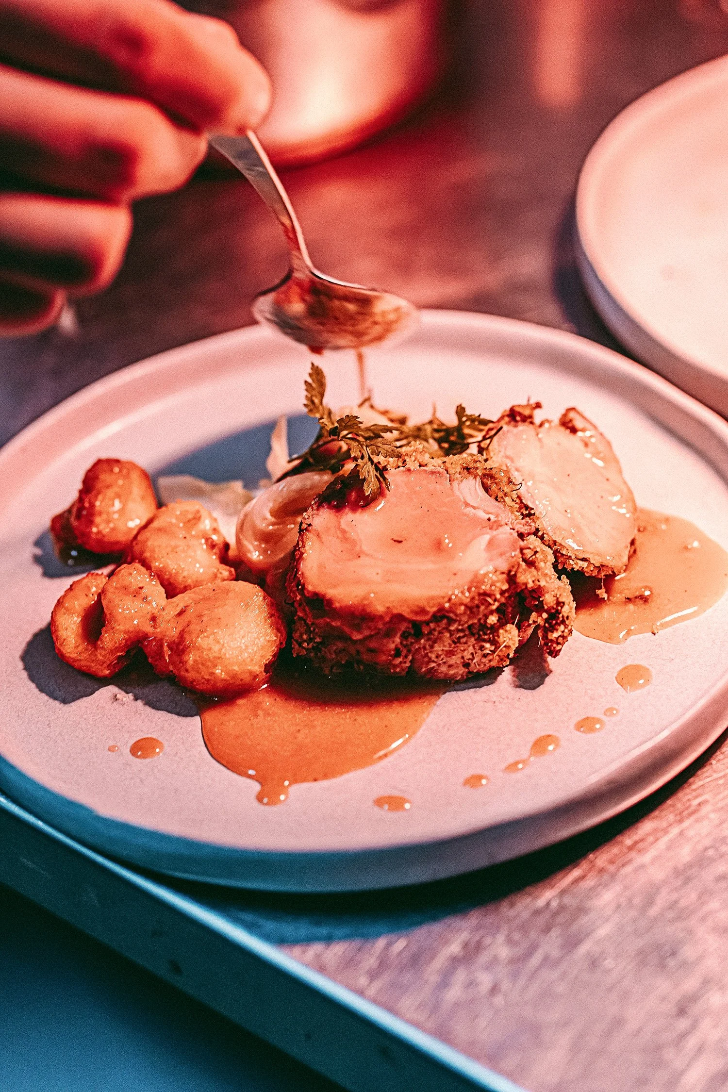 Plat de viande avec geste de main mettant une sauce.