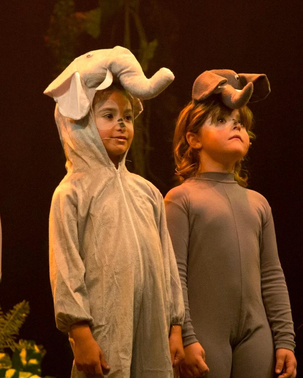 Niños disfrazados de elefantes en una presentación teatral.