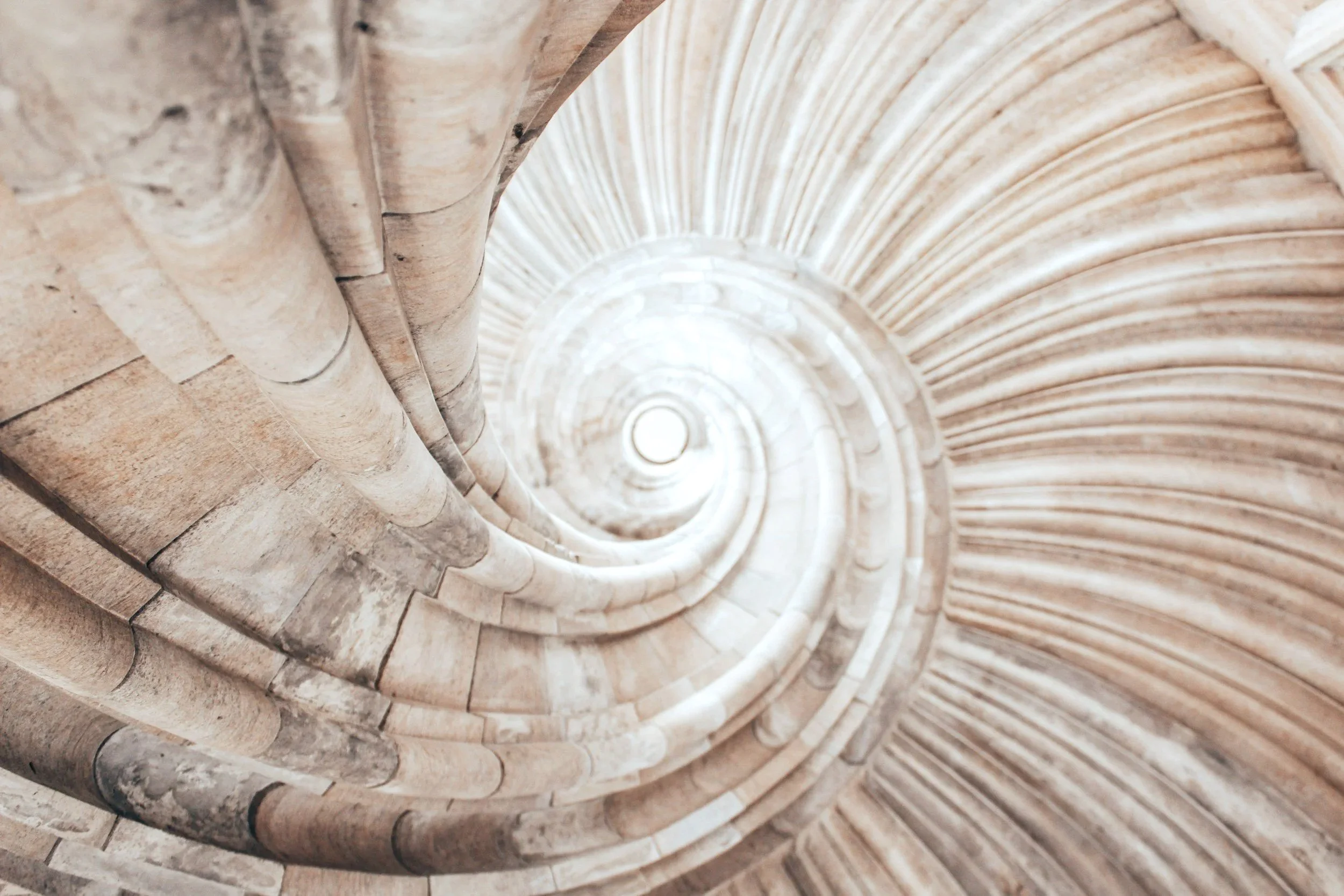 Vista desde abajo de una escalera de caracol de piedra, mostrando el patrón circular que se forma.