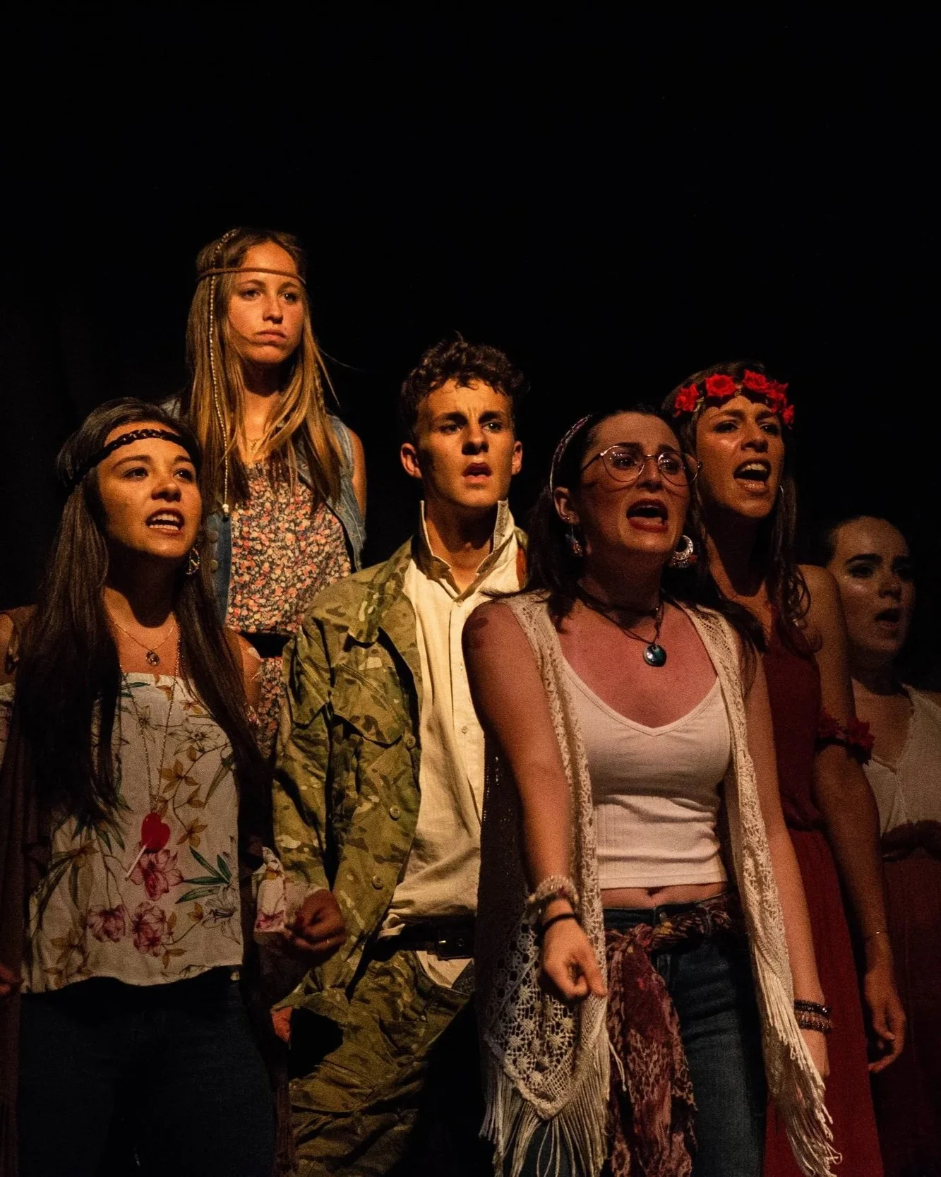 Grupo de personas en escena, probablemente durante una obra teatral o un concierto, expresando emociones intensas.