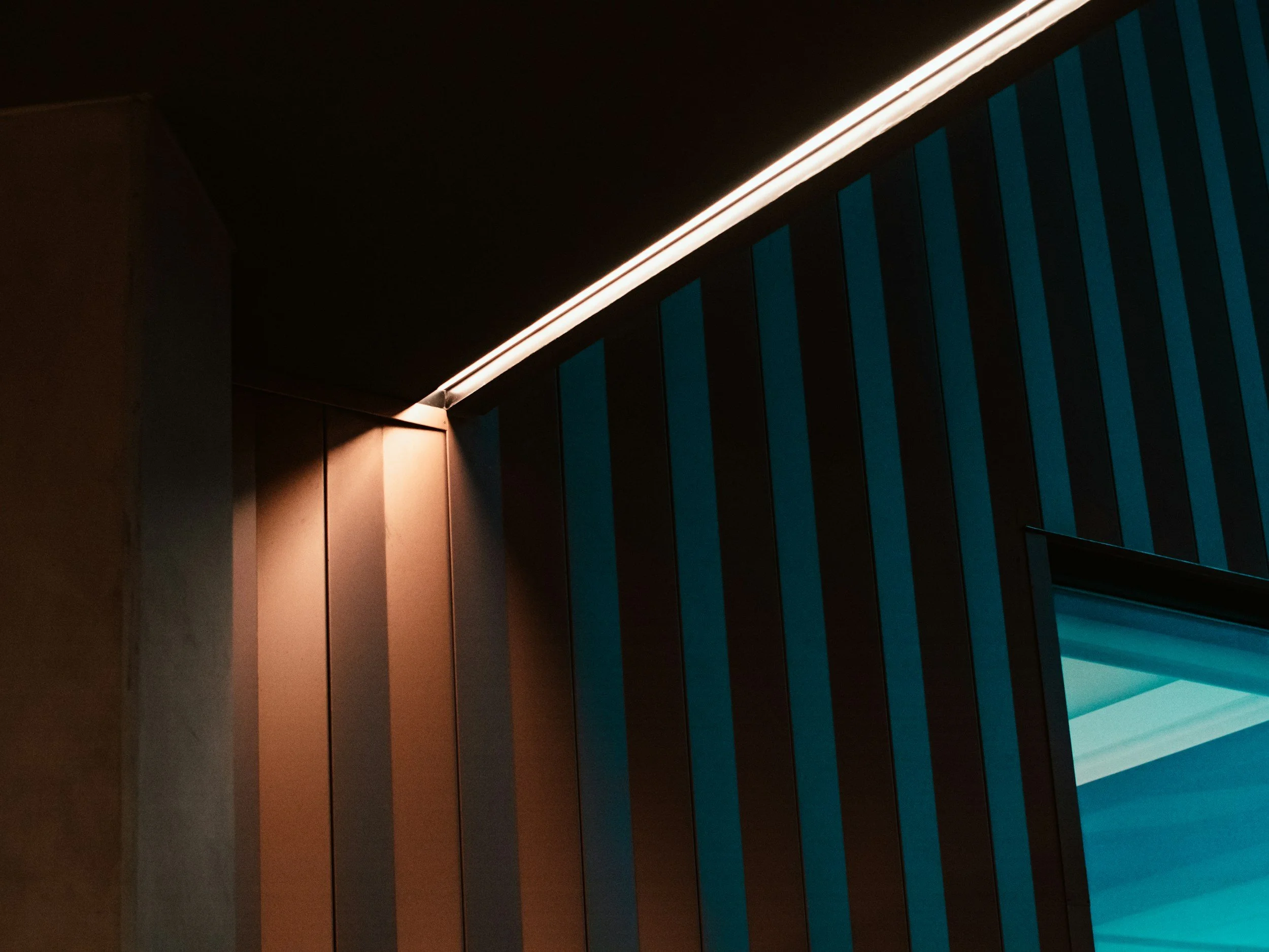 Close-up of architectural elements with illuminated edges and vertical blue panels, possibly part of a modern building's interior or exterior design.