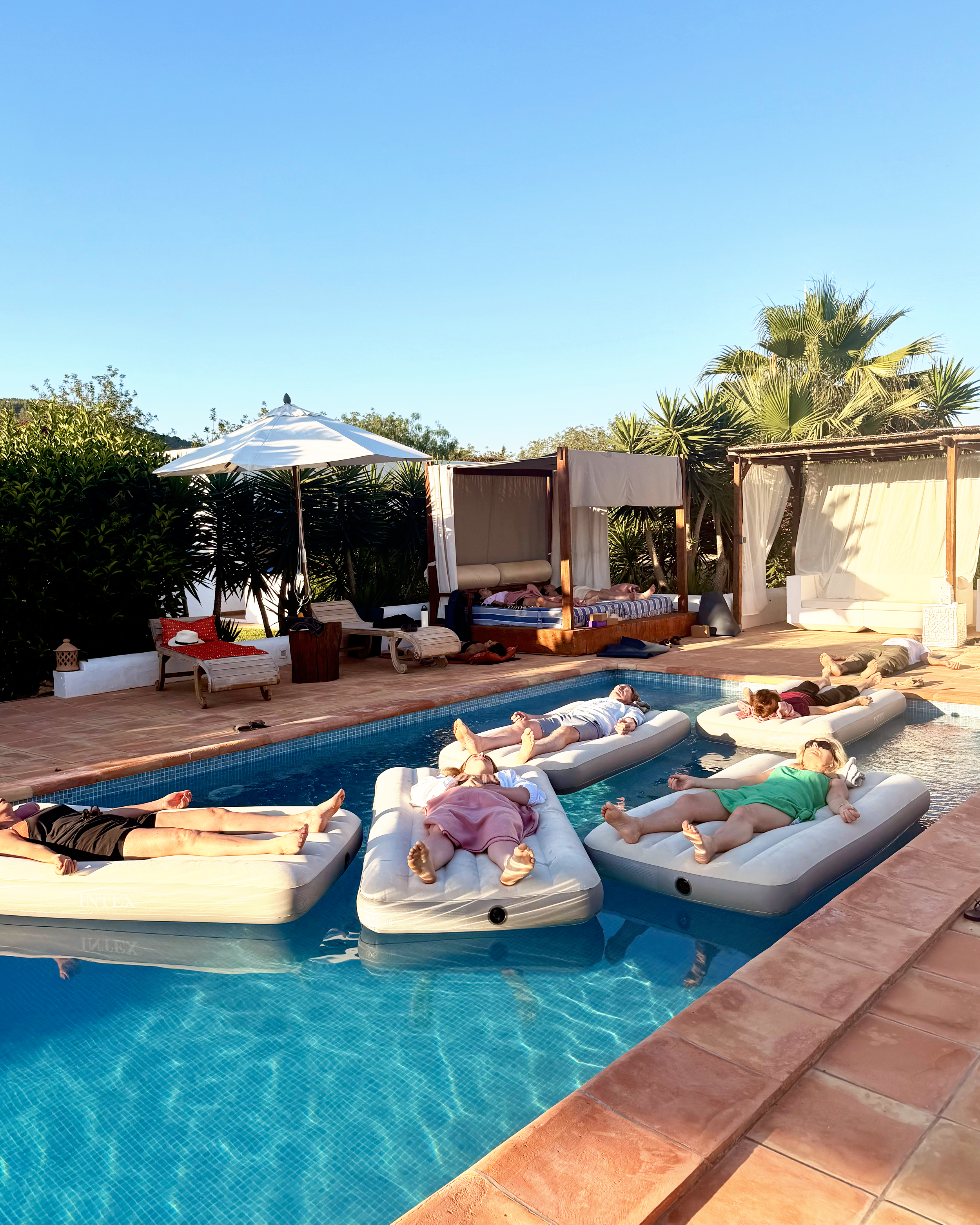 mannen en vrouwen in zwembad op een luchtbed tijdens een yoga nidra sessie tijdens het Ibiza retreat van YOGADNA onder leiding van Seth Kamphuijs.