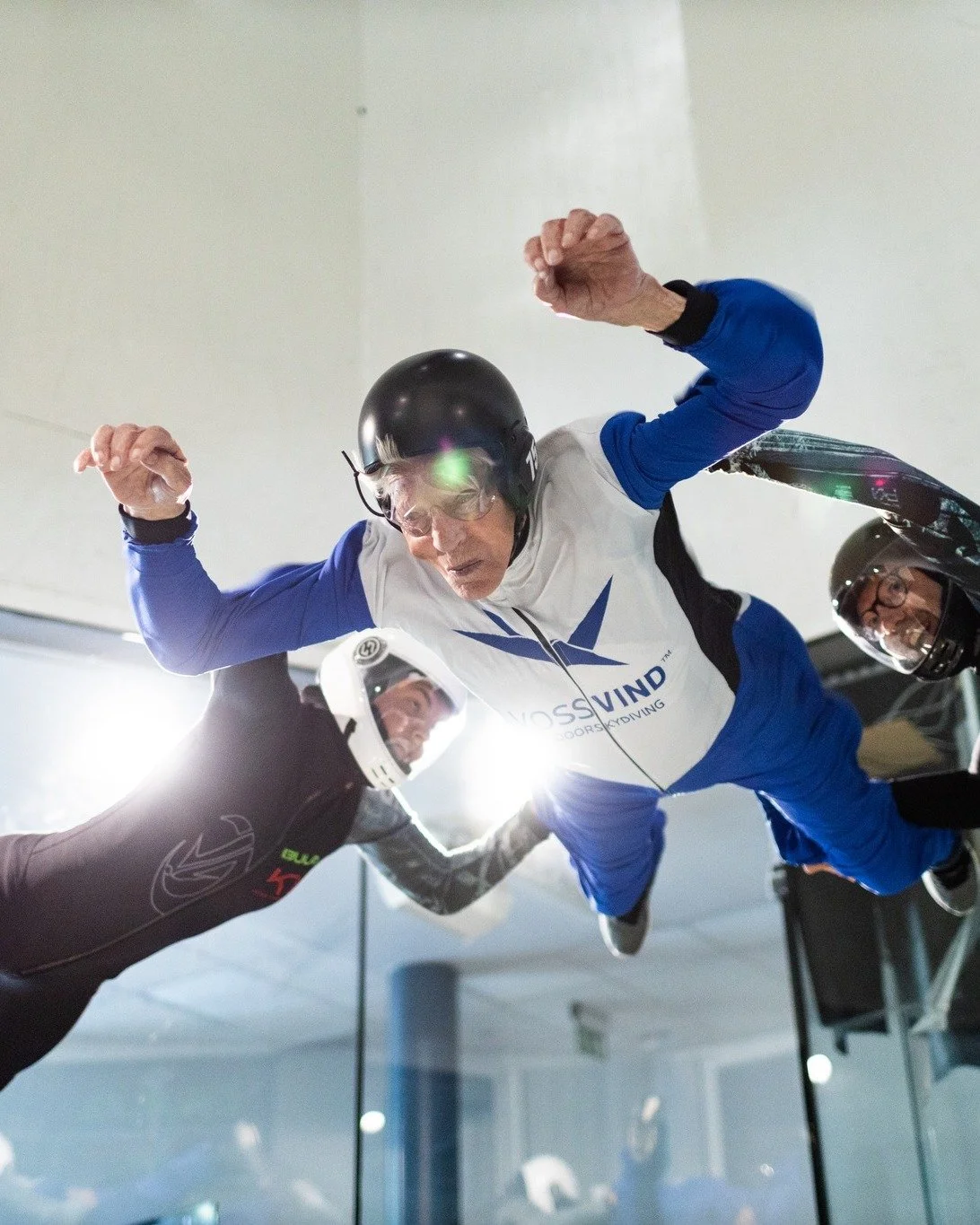 En eldre herre flyr i vindtunnel. Får hjelp av instruktører.