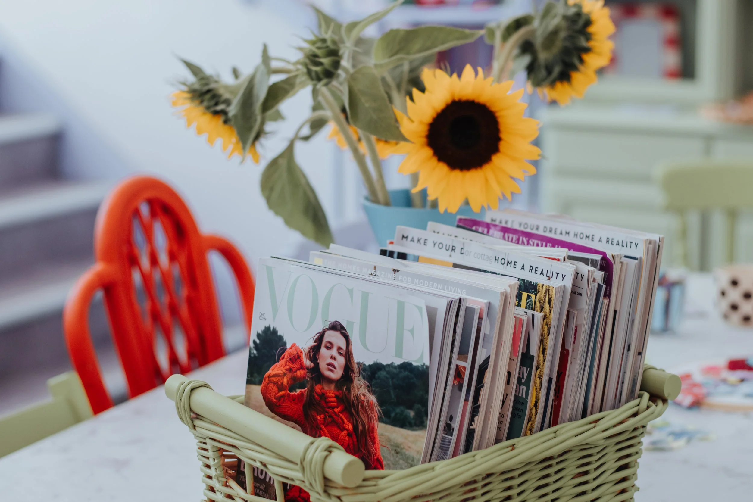 Close up of the Studio's Workshop Table, including a gorgeous vase of Sunflowers and a Green Basket of Magazines/