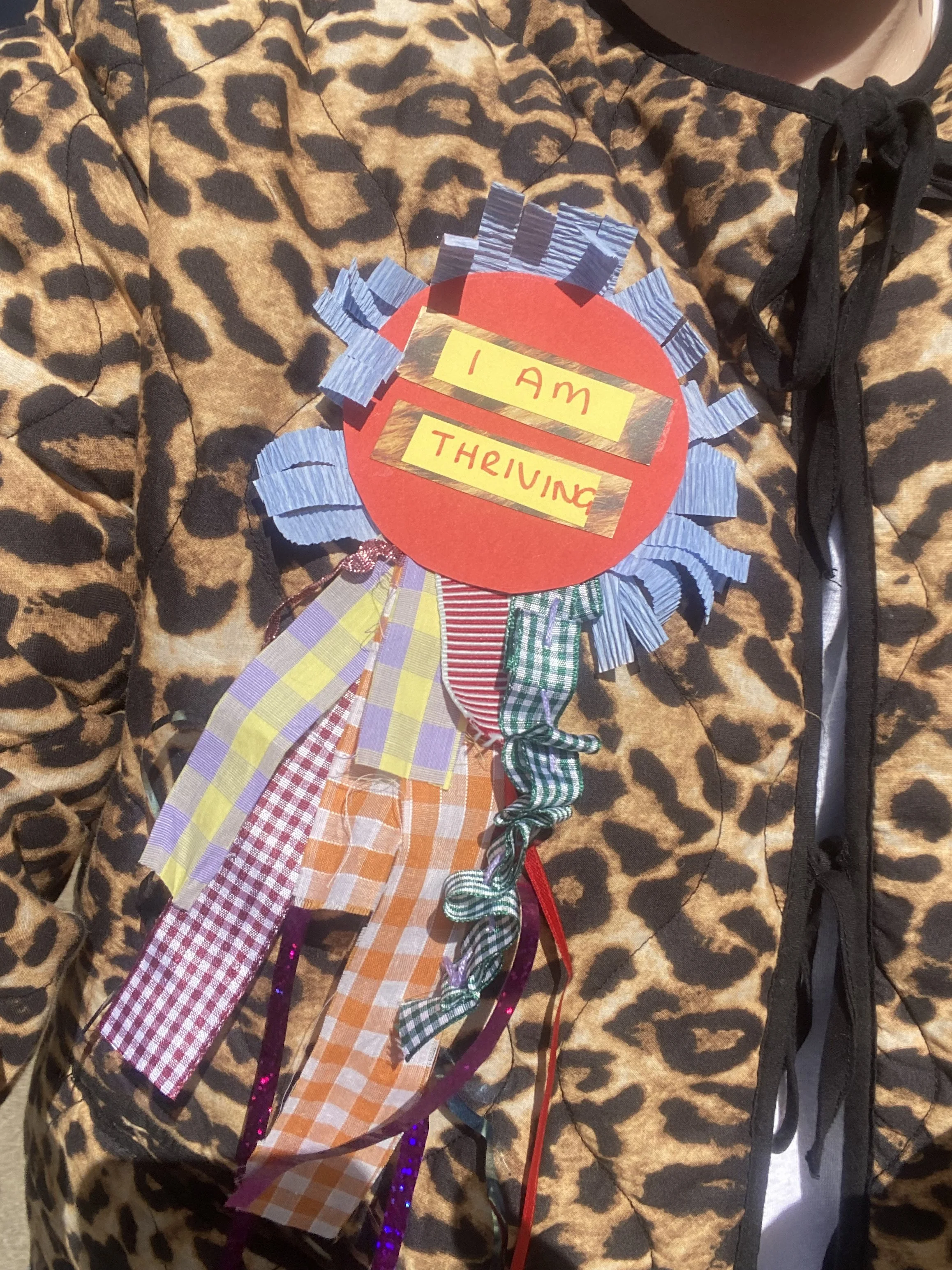 Creative Babe wears a hand crafted 'I am Thriving' Affirmation Badge, with Paper, Fabrics and Ribbons on a Leopard Print Jacket.